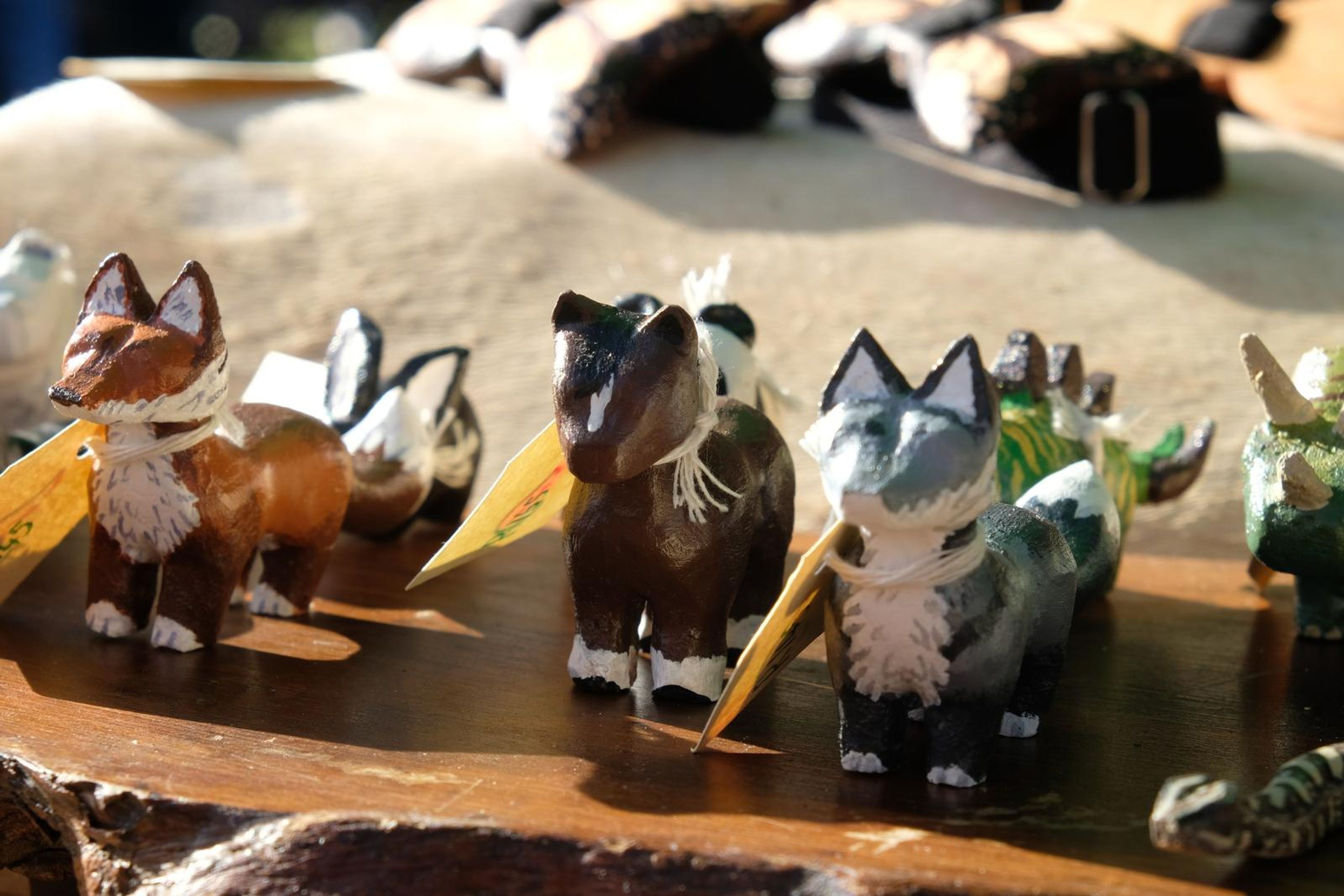 Hand-carved wooden animals with handwritten tags beside leather cuffs