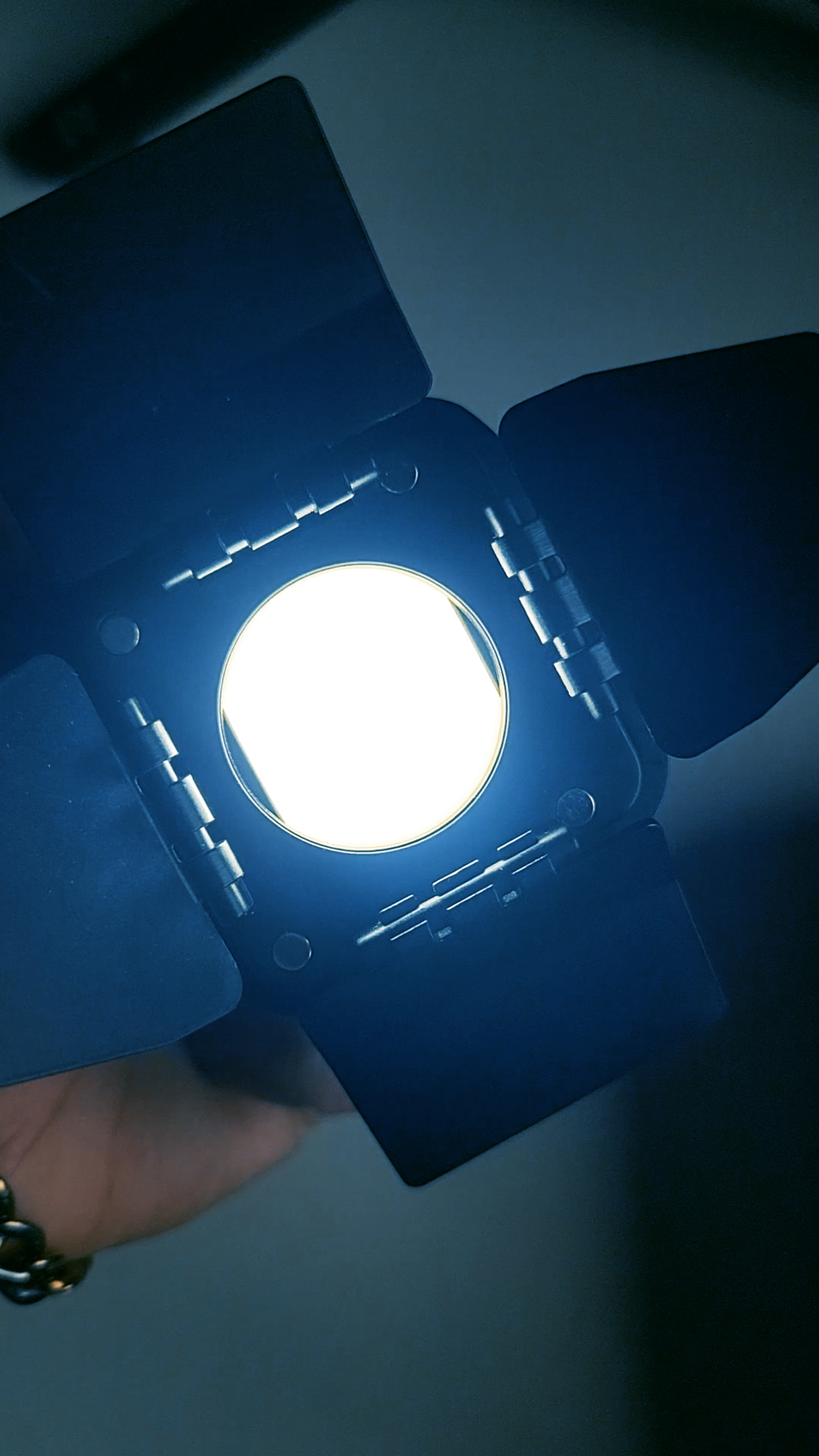 Behind the scenes, a studio light with barn doors glowing bright blue