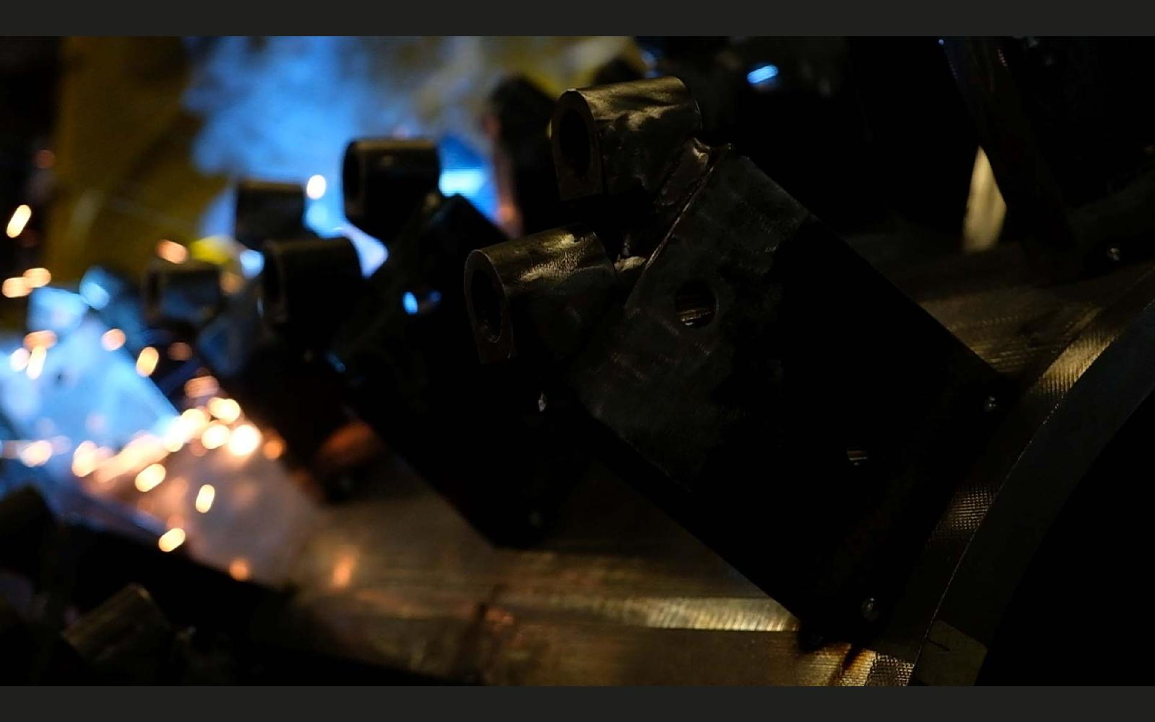 Welder welding steel brackets on a large drum with a bright arc