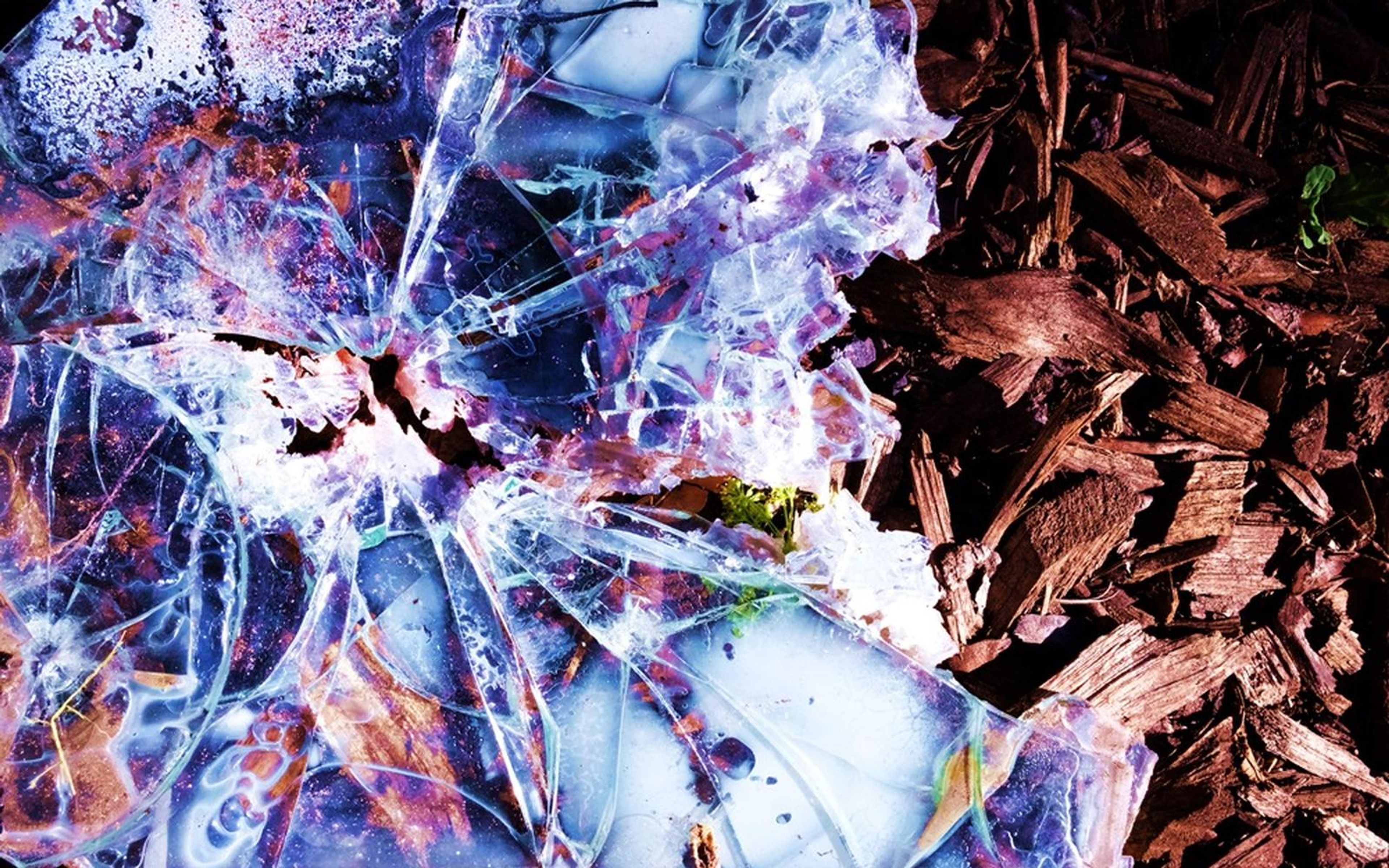 Shattered glass in blue and purple tones beside red-brown wood chips