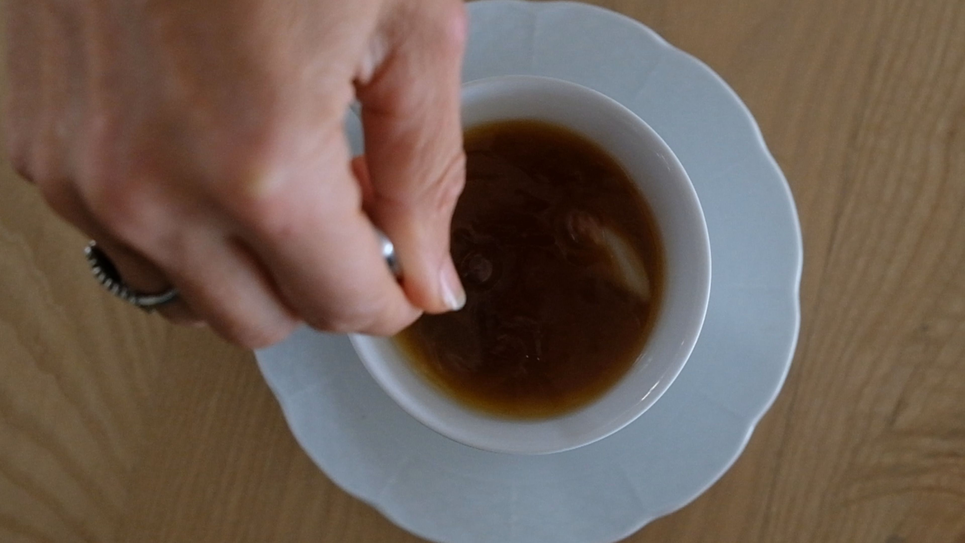 Hand squeezing a lemon juice sachet into a cup of tea