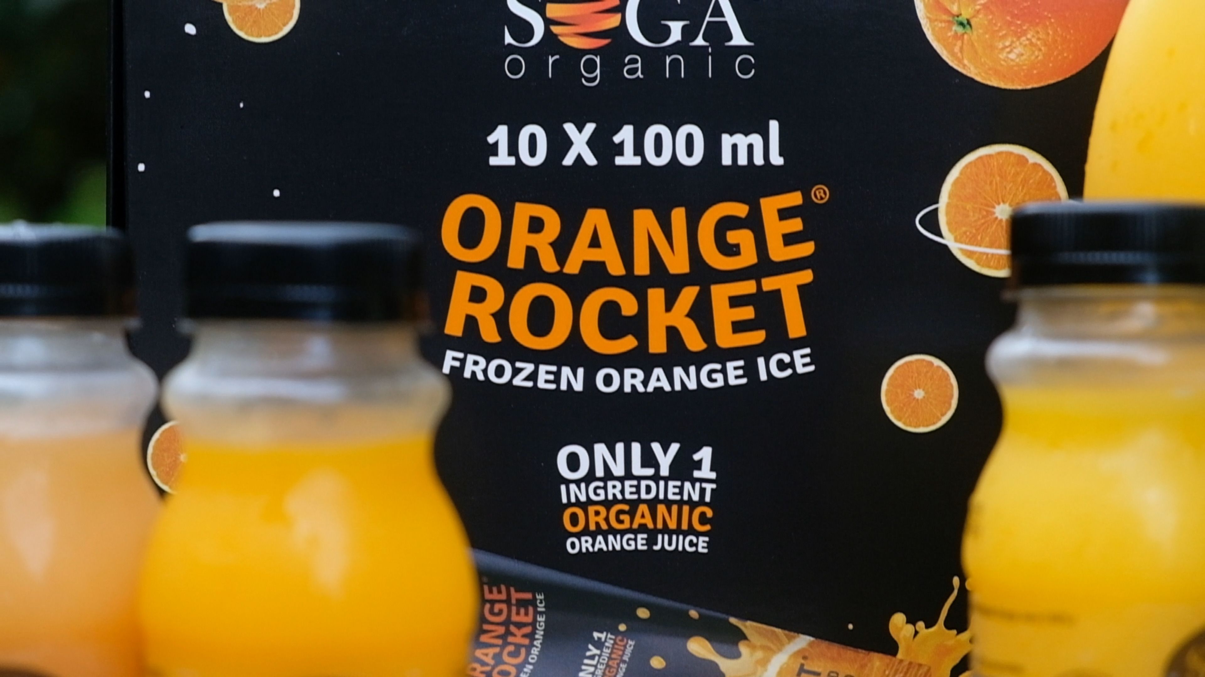 Close-up of the SOGA Orange Rocket 10 x 100 ml box with orange juice bottles beside it