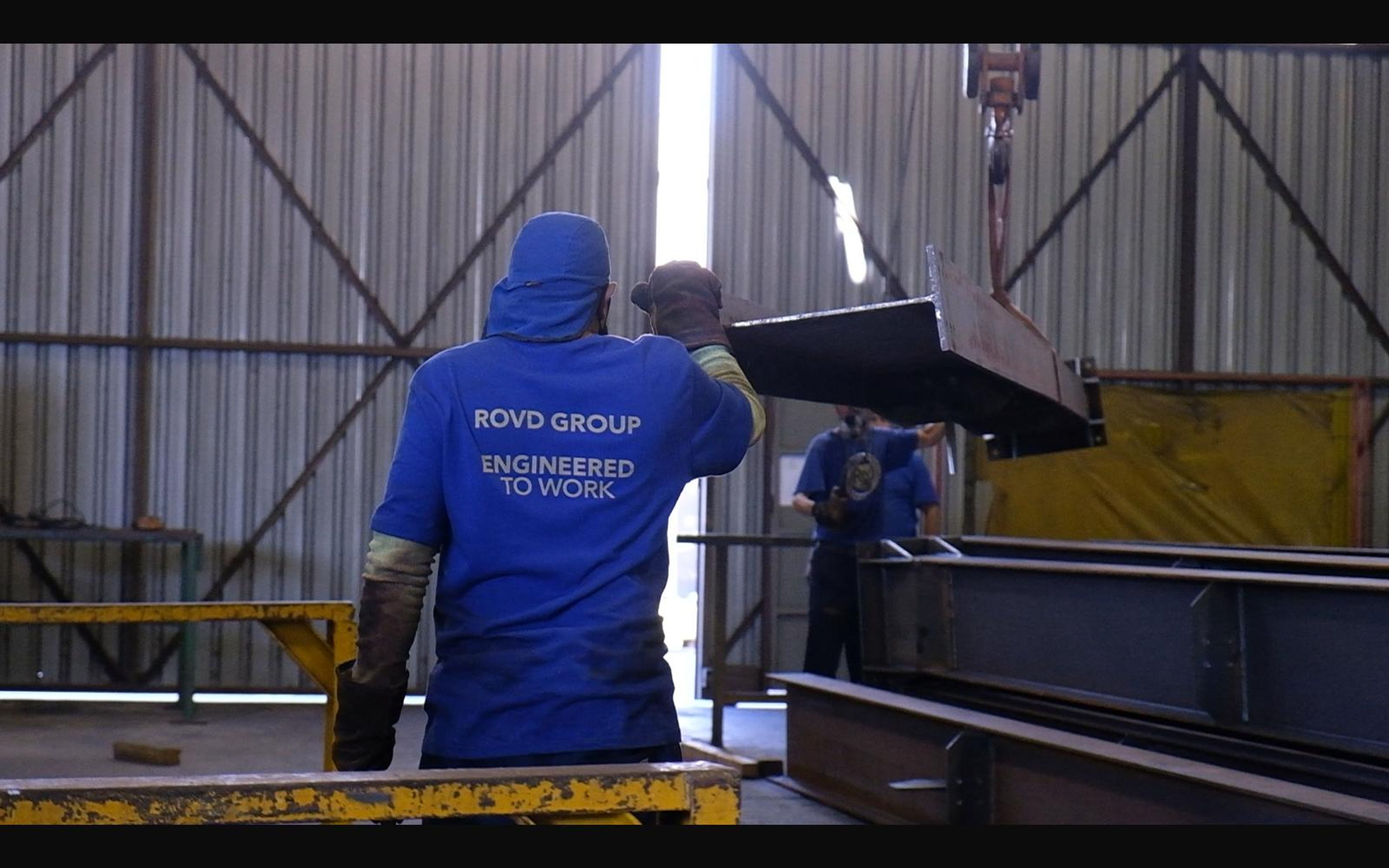 Worker guiding a steel plate on a crane