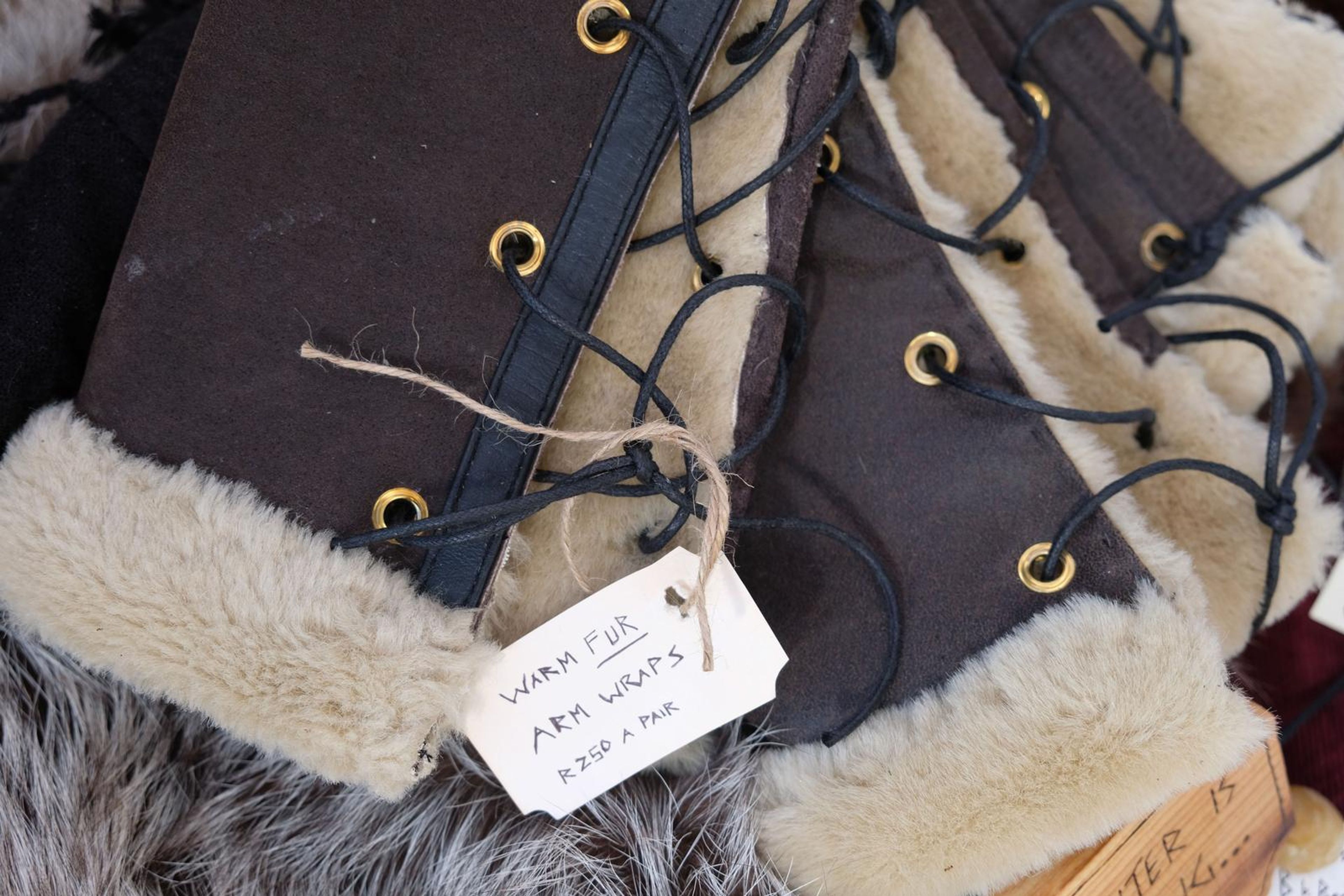 Close-up of fur-lined leather arm wraps with eyelets and black lacing
