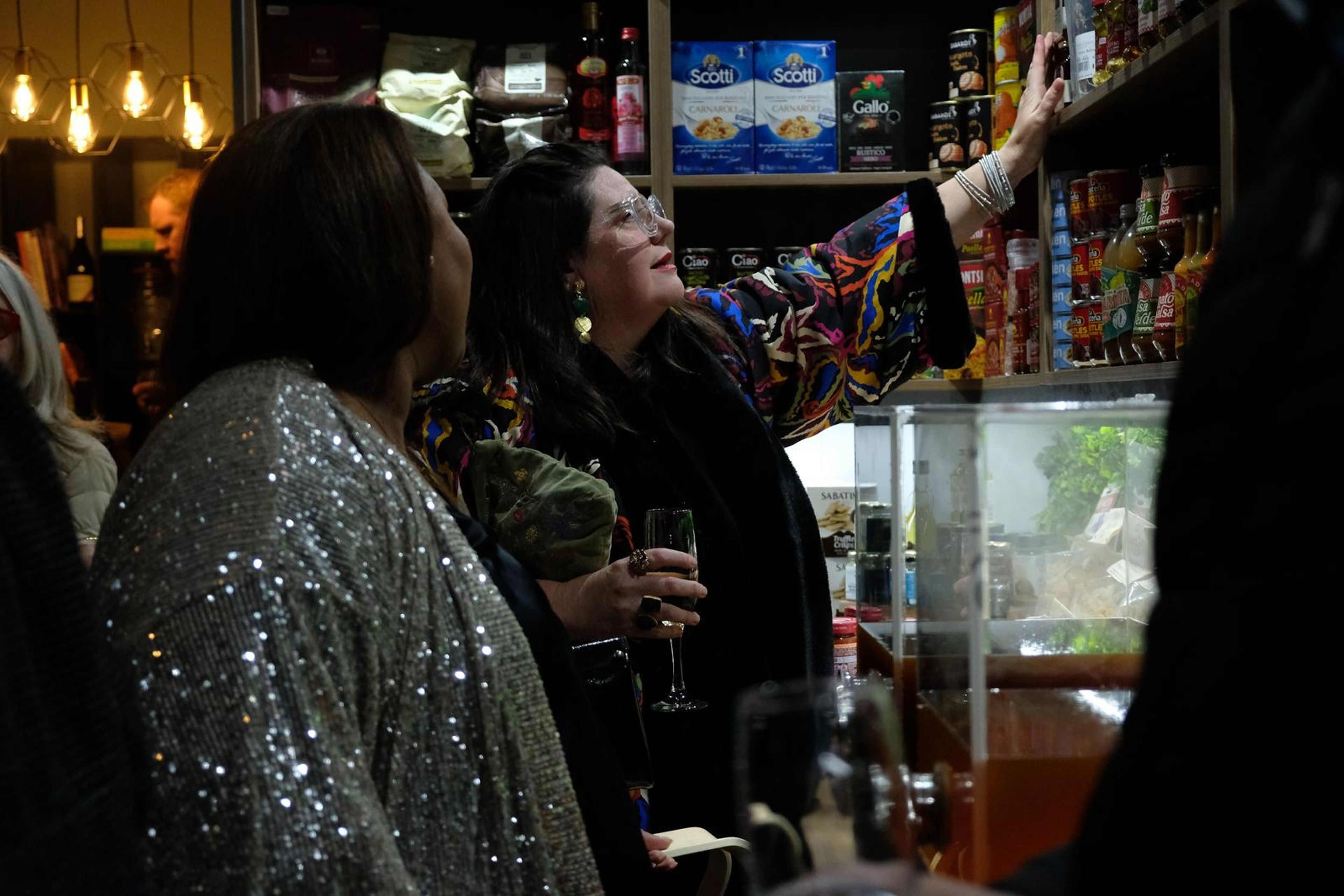 Guests with glasses of champagne looking up at the pantry shelves