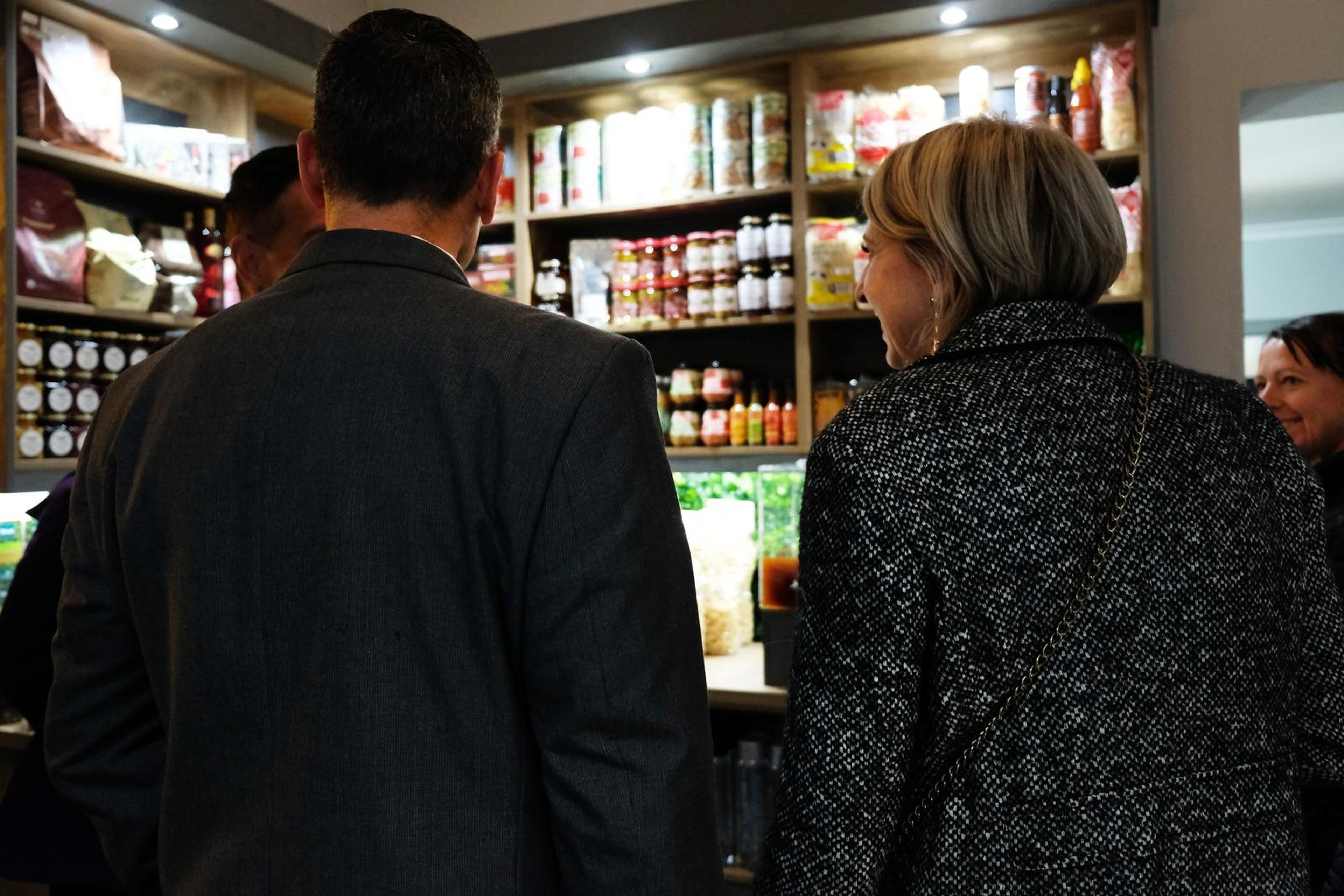 Guests seen from behind talking in front of shelves of jars and pasta