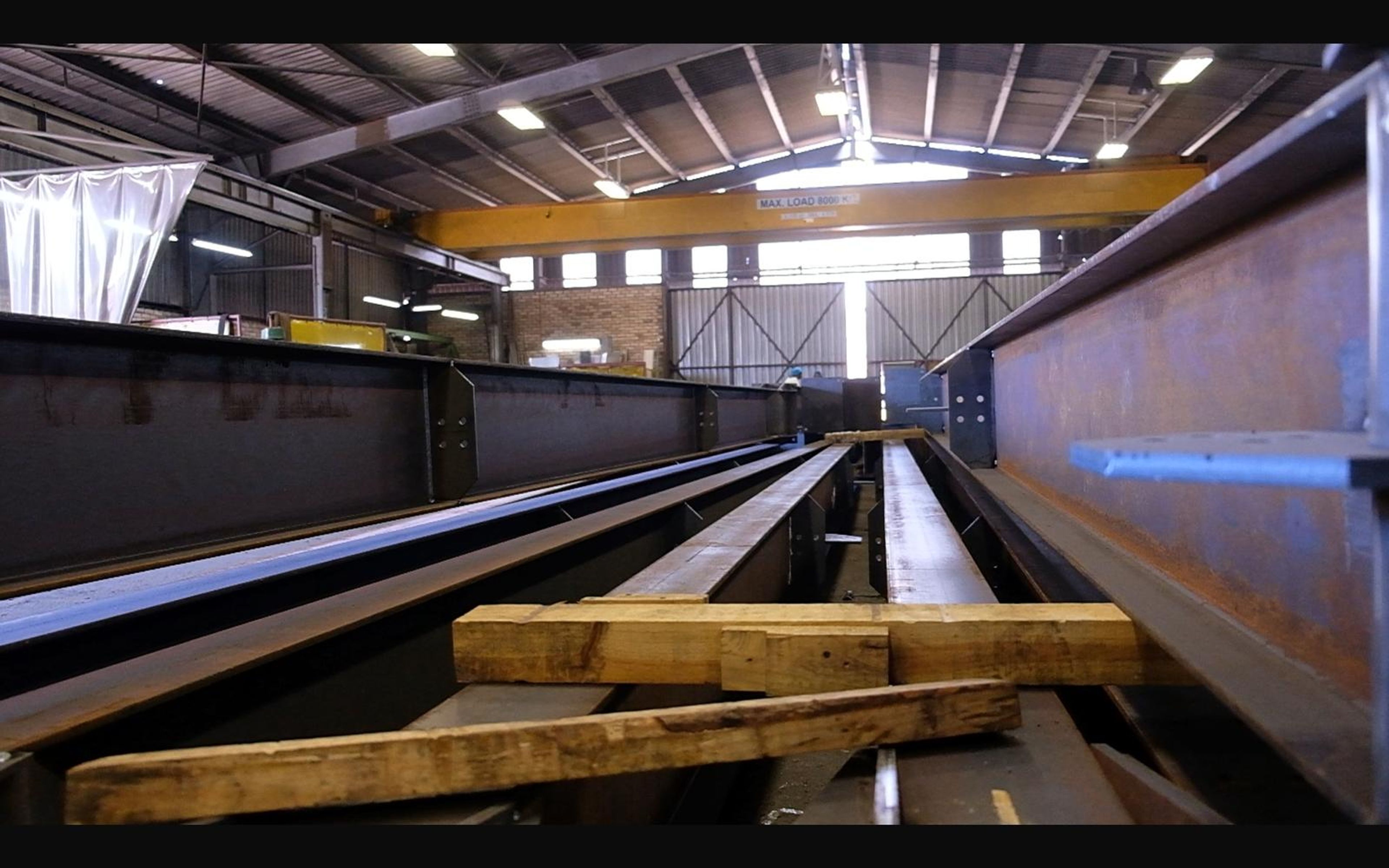 Row of steel beams laid out along the shop floor