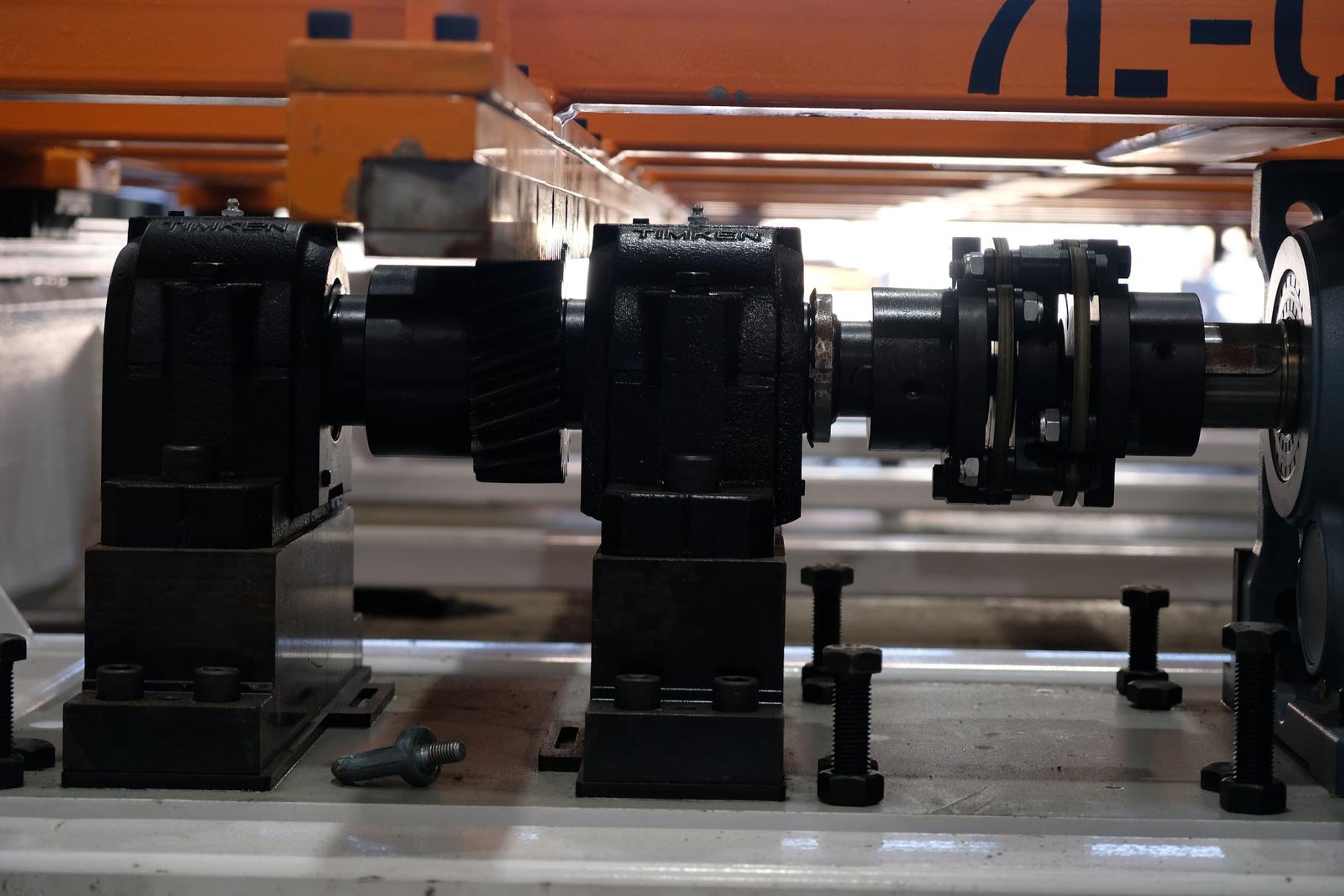 Bearing housings and a drive shaft running to a motor beneath an orange beam