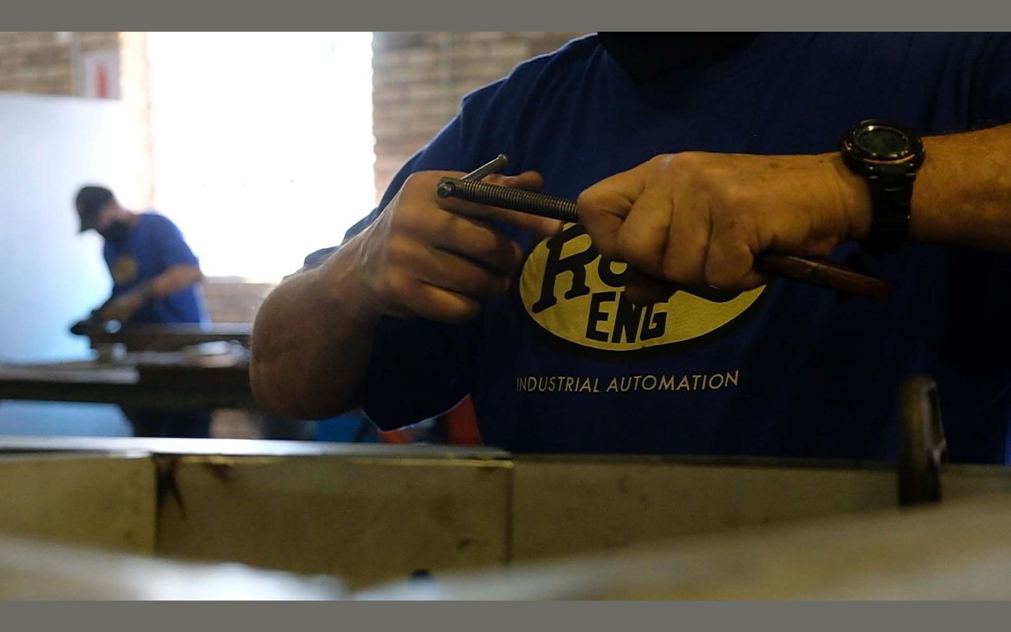 Fabricator in a ROVD shirt working at a steel bench
