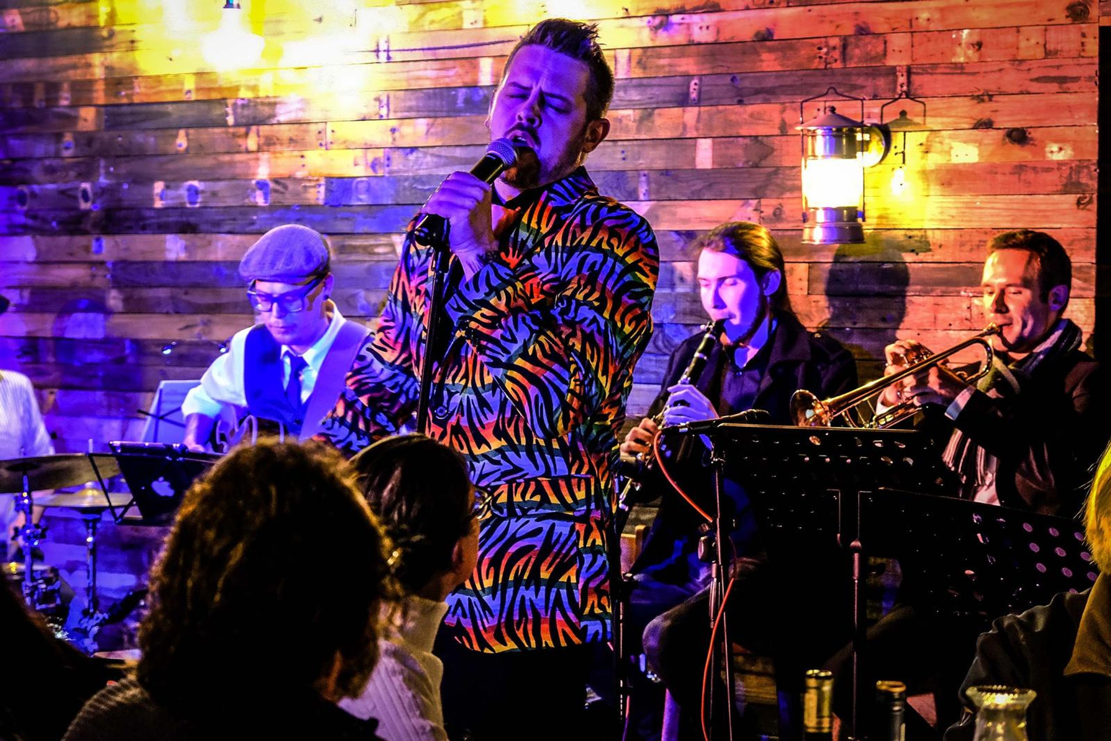 Lead singer in a rainbow zebra jacket singing in front of the horn section