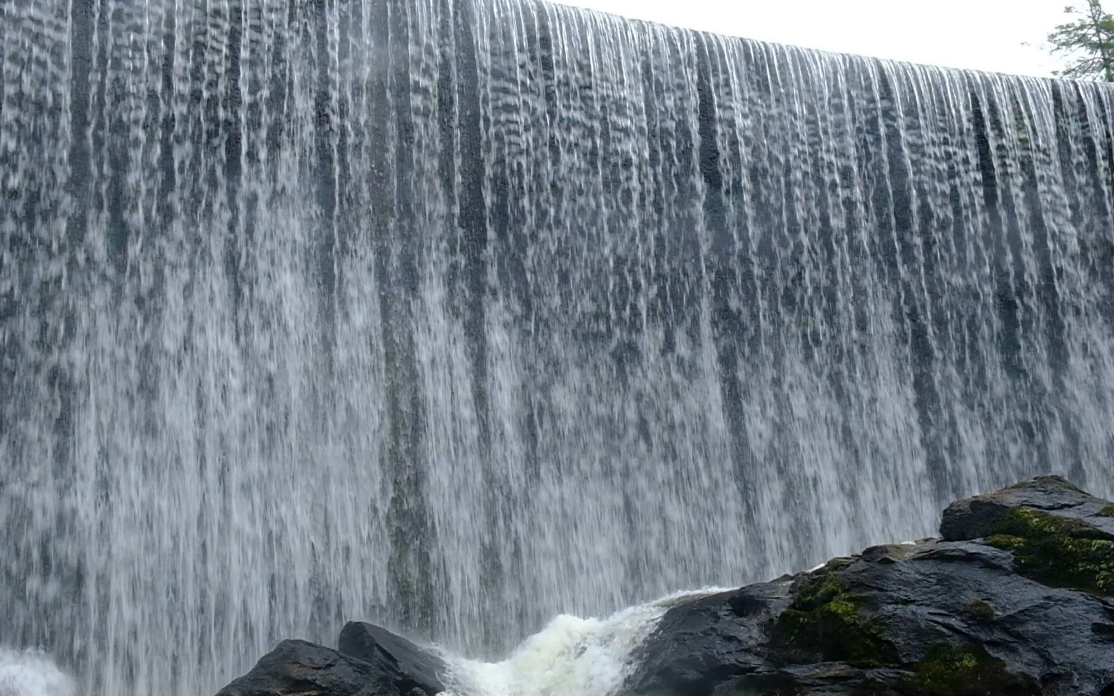 Close view of the full waterfall curtain falling over its edge above dark rocks