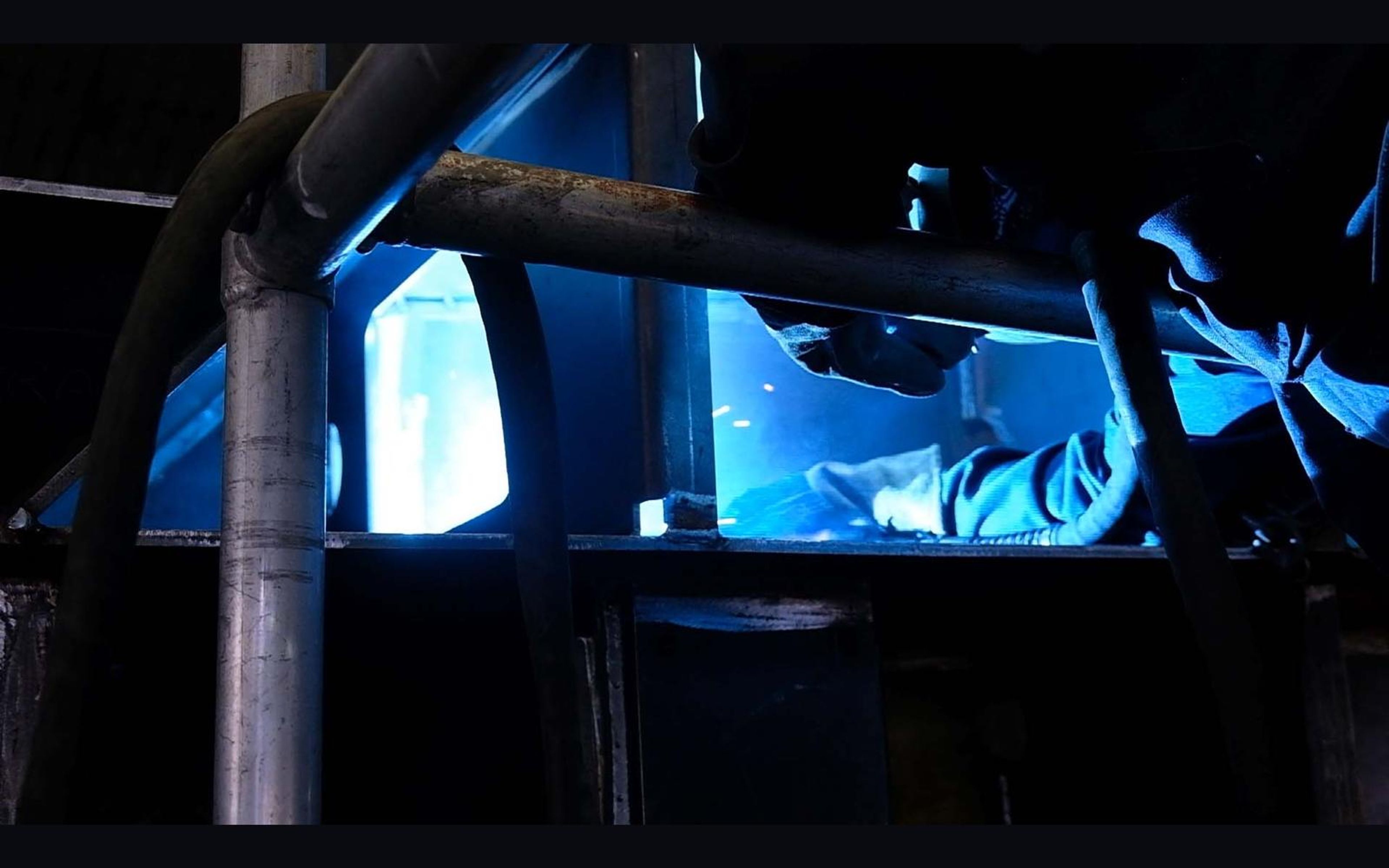 Welder in a mask working in bright blue arc light