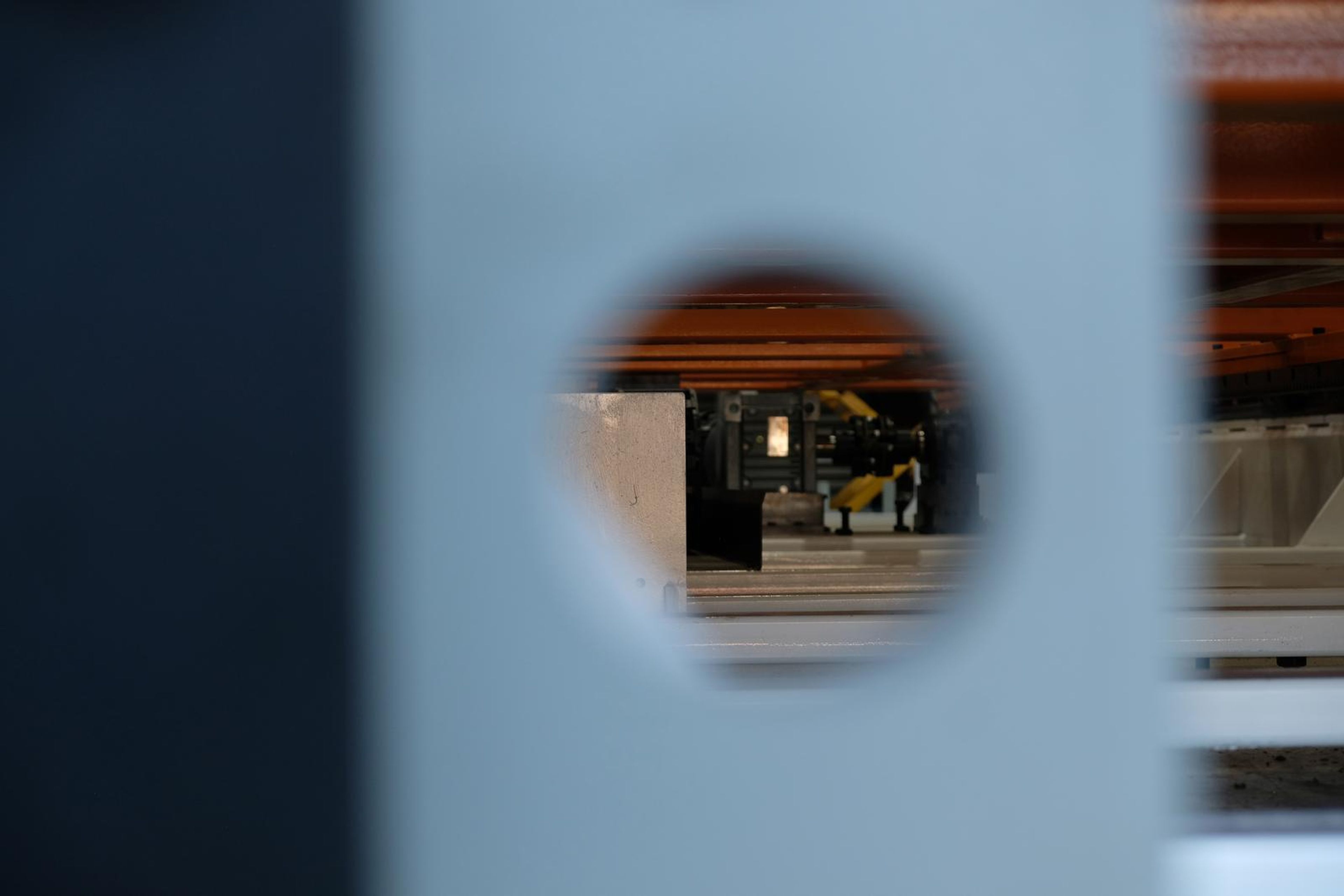 Hole punched through a grey steel upright with the plant visible beyond