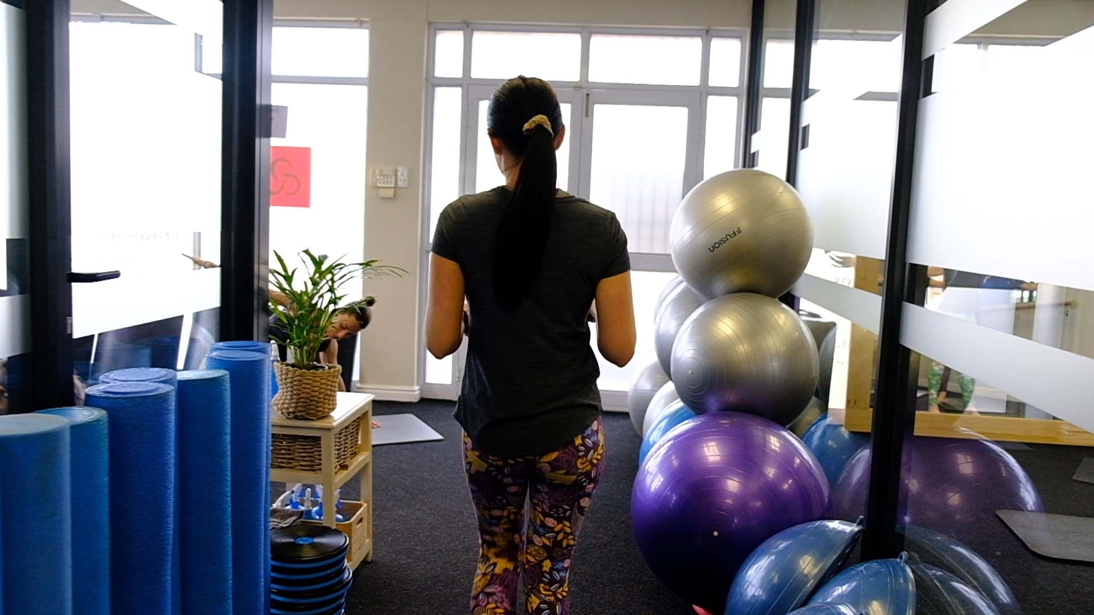 Staff member walking through the studio past stacked stability balls