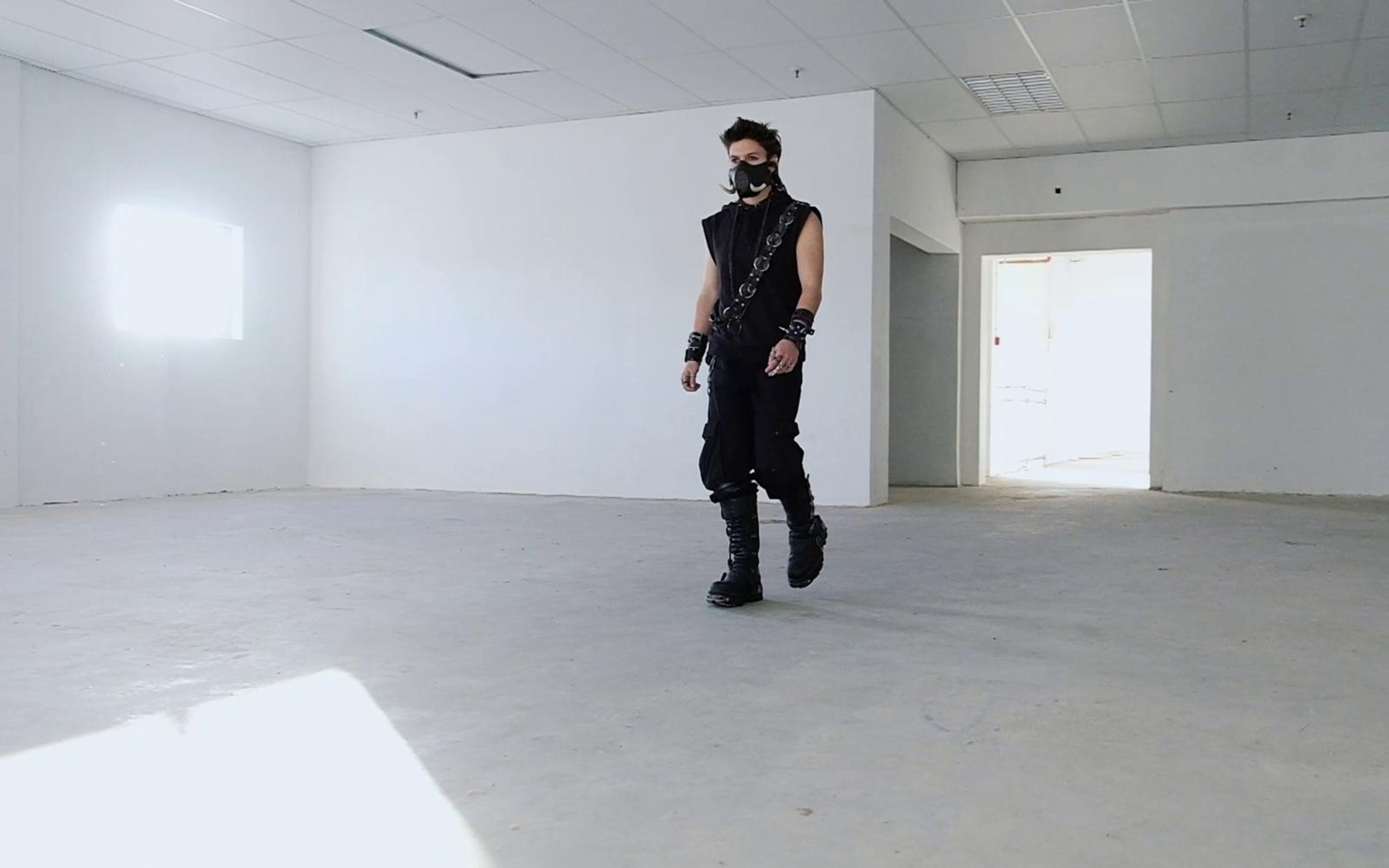 Warrior stepping forward in a large bare room with a lit doorway at the right