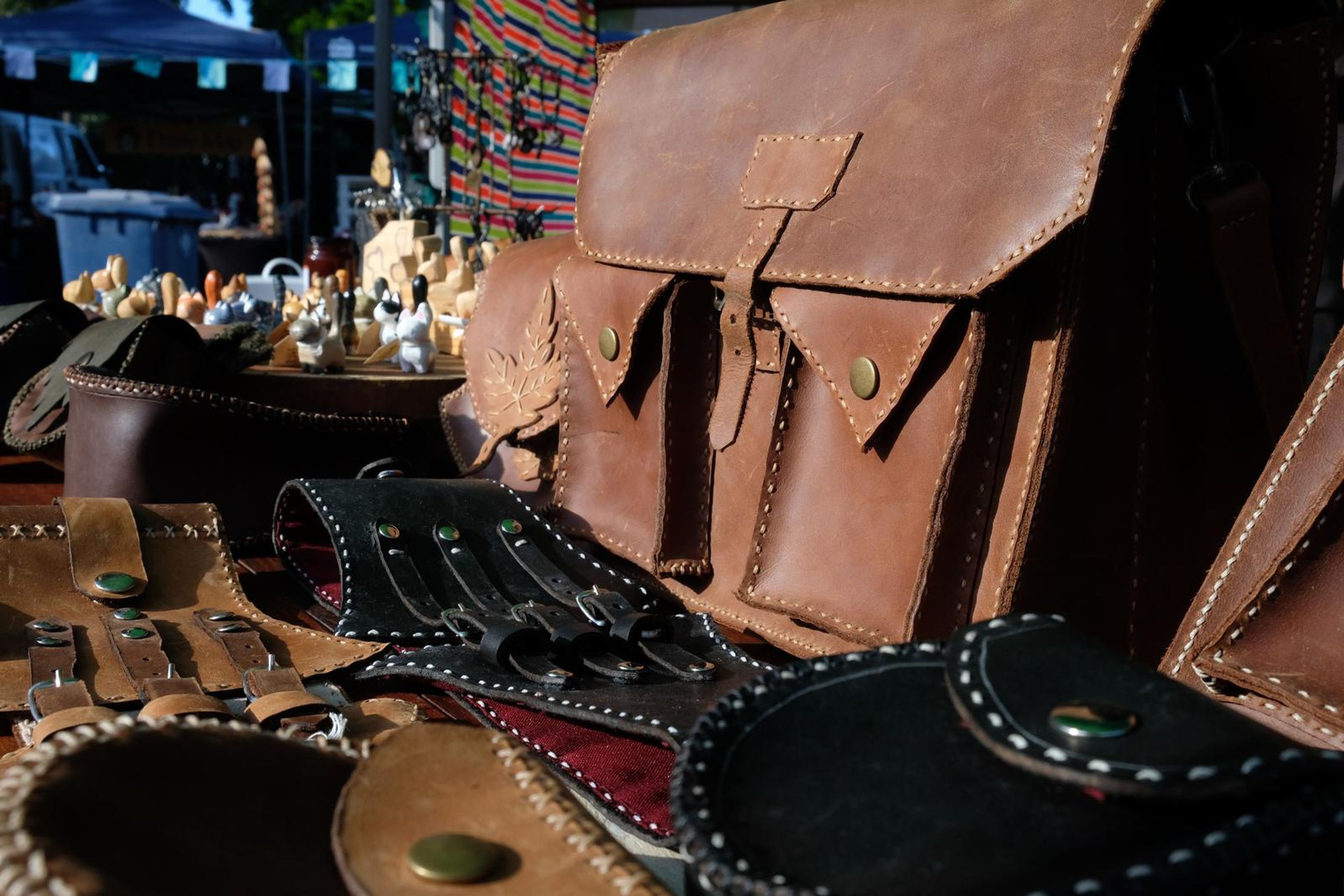 Tan leather satchel beside black corset belts at the Juuks stall