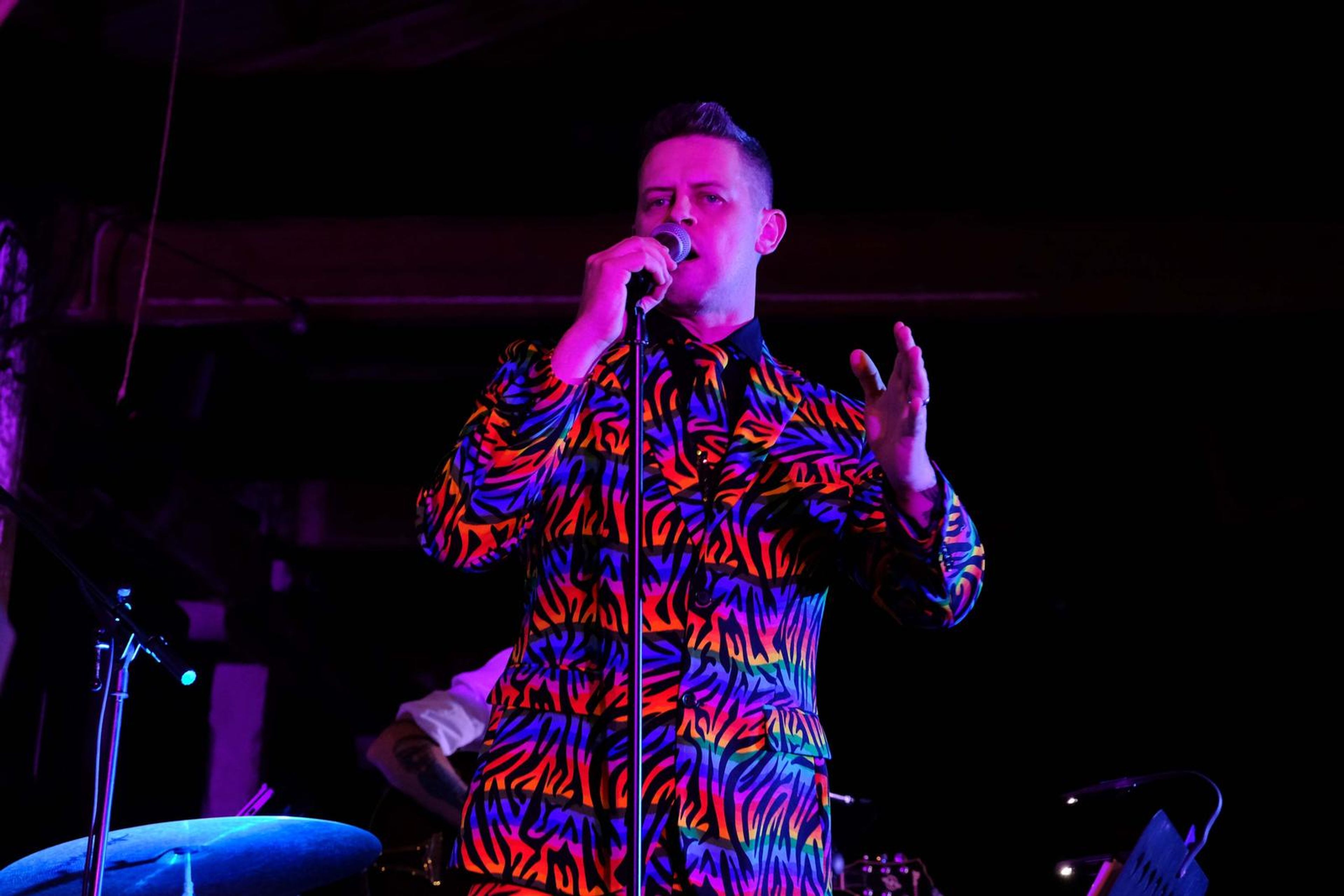 Singer in a rainbow zebra jacket singing to the crowd