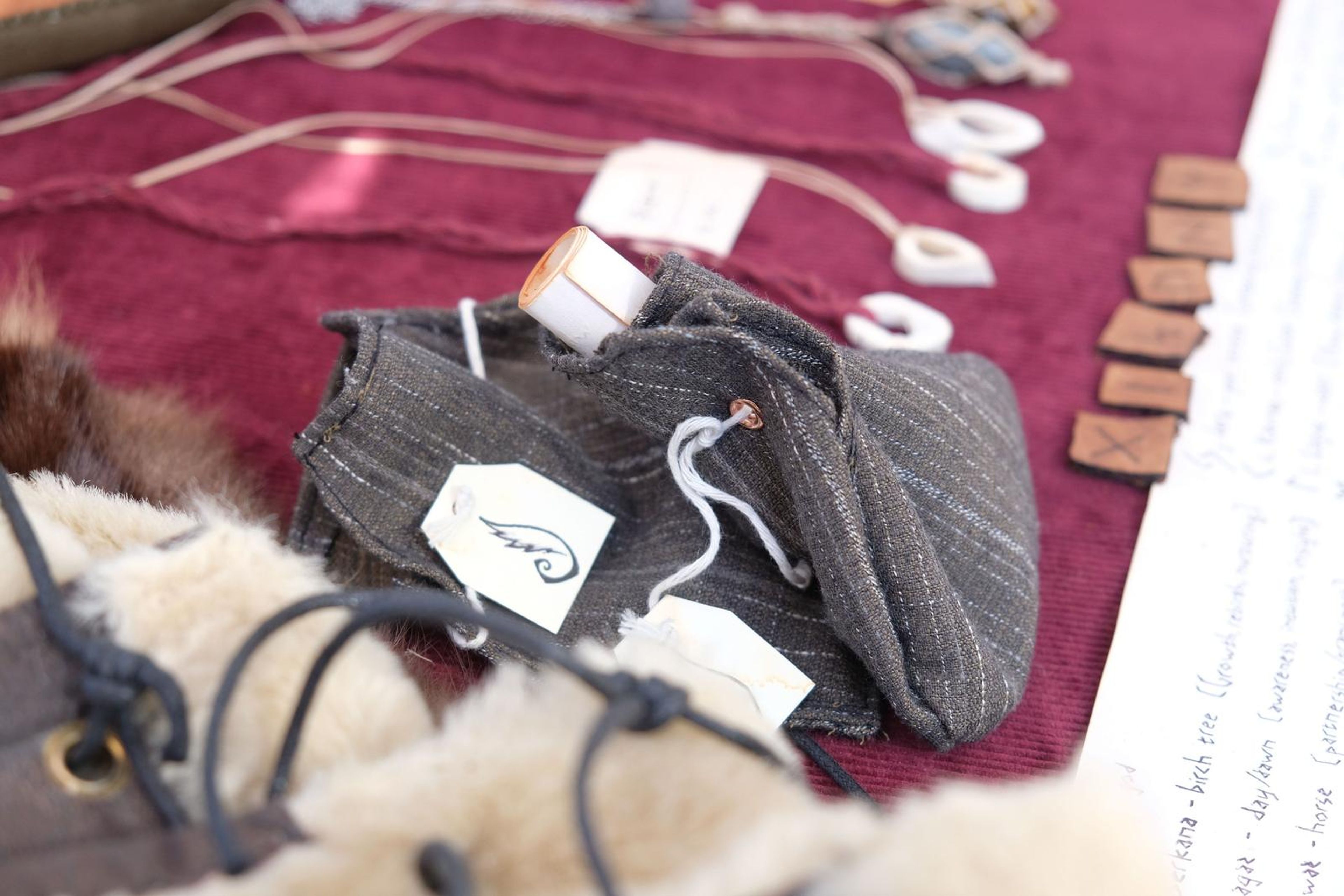 Grey striped cap beside fur-lined leather and a rune alphabet sheet