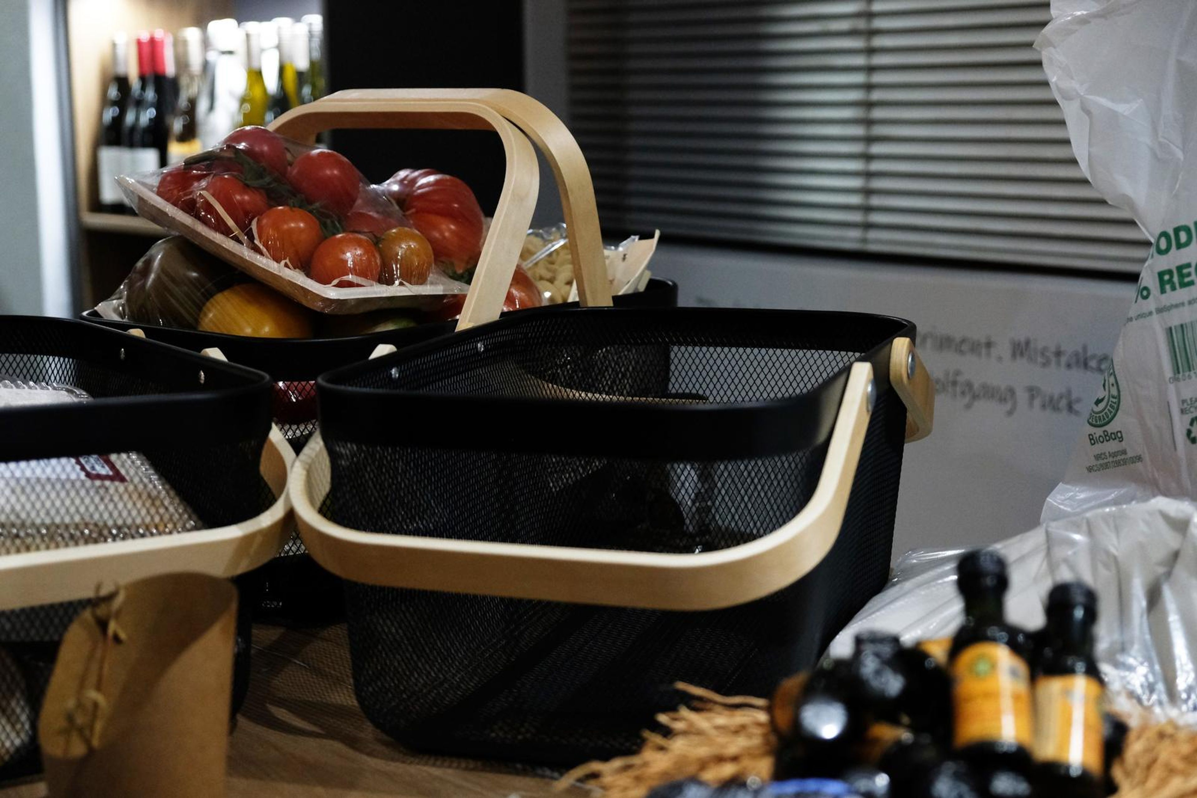 Two baskets of tomatoes and bottles on the counter