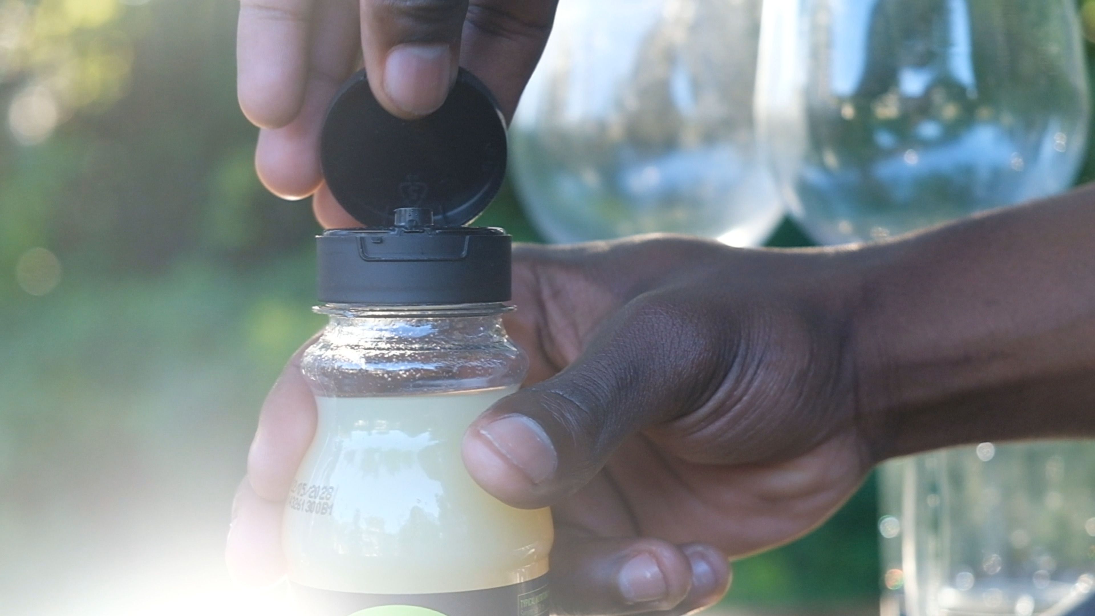 Hand opening the flip cap of a small bottle of frozen lemon juice