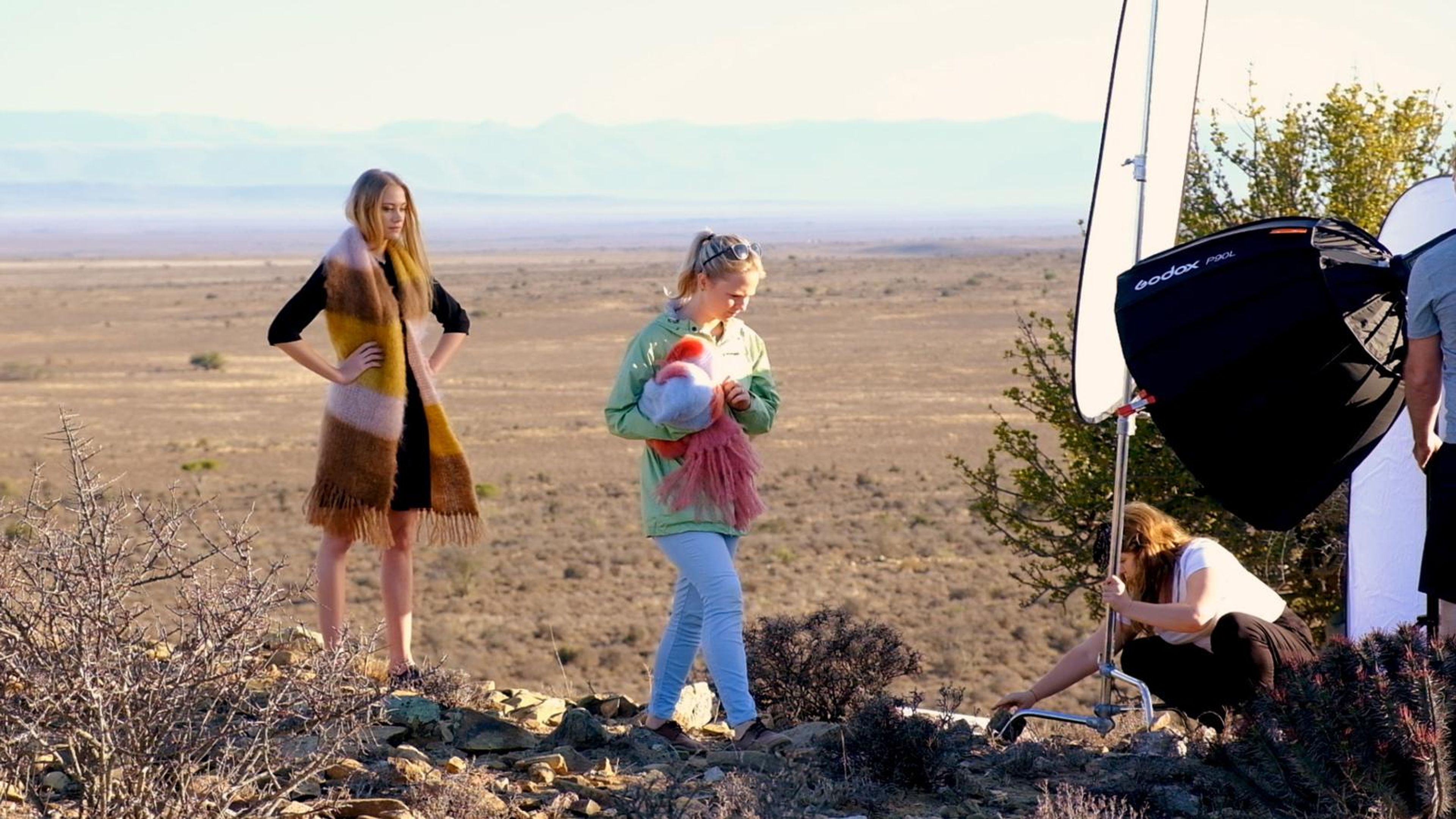 Model and stylist posing beside a softbox on a hilltop