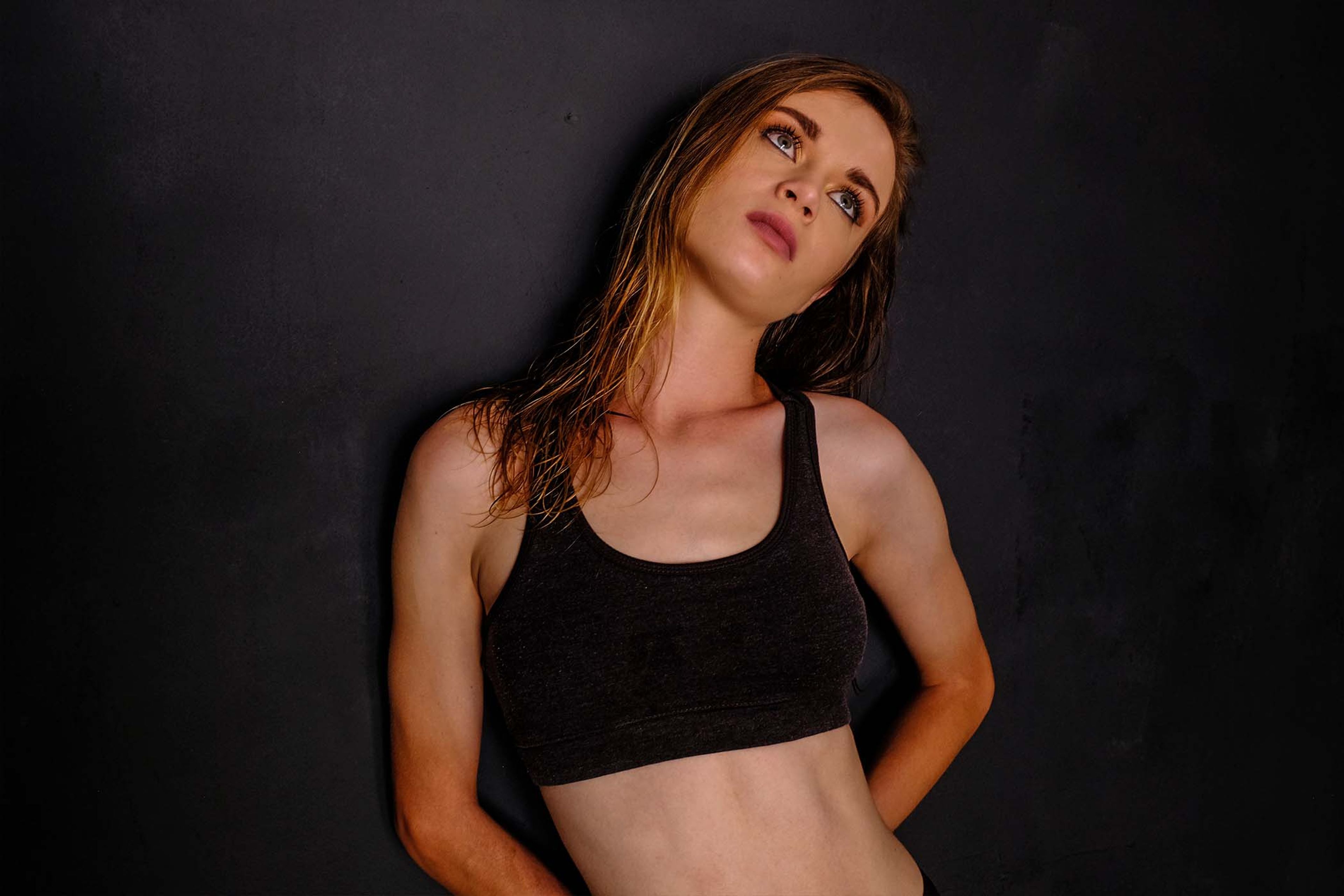 Portrait, subject in a fitted sports bra looking upward, dramatic side lighting