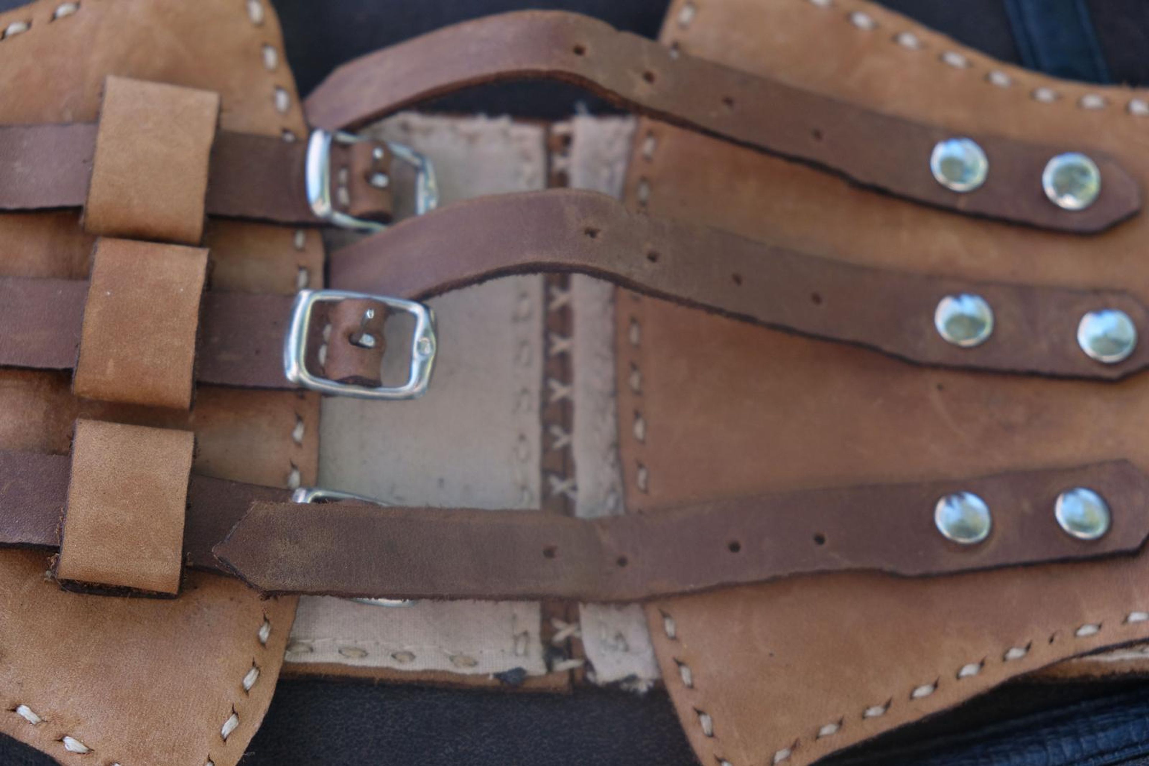 Close-up of tan and brown buckled leather straps with a handwritten tag