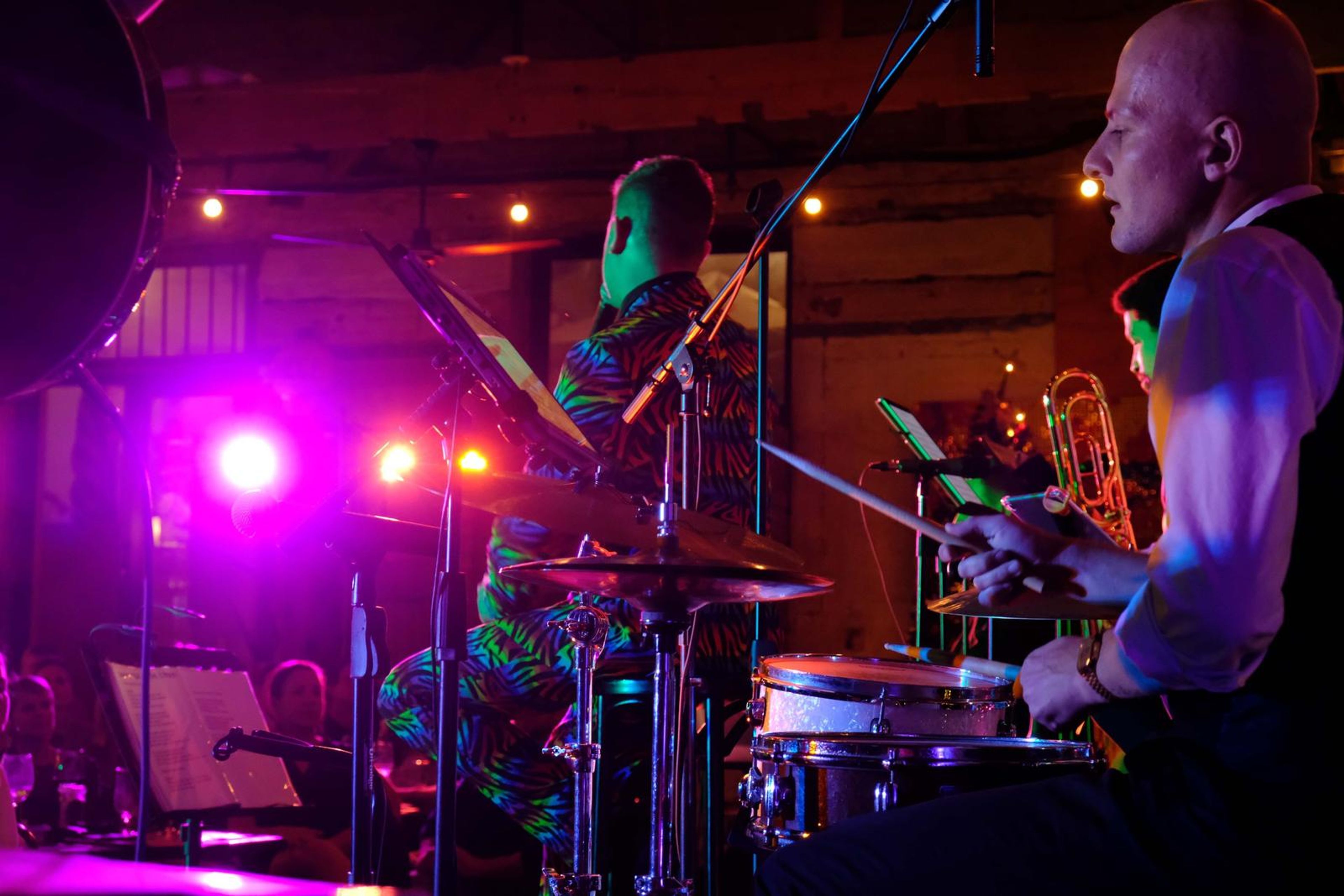 Drummer in rainbow trousers and a horn player in pink light