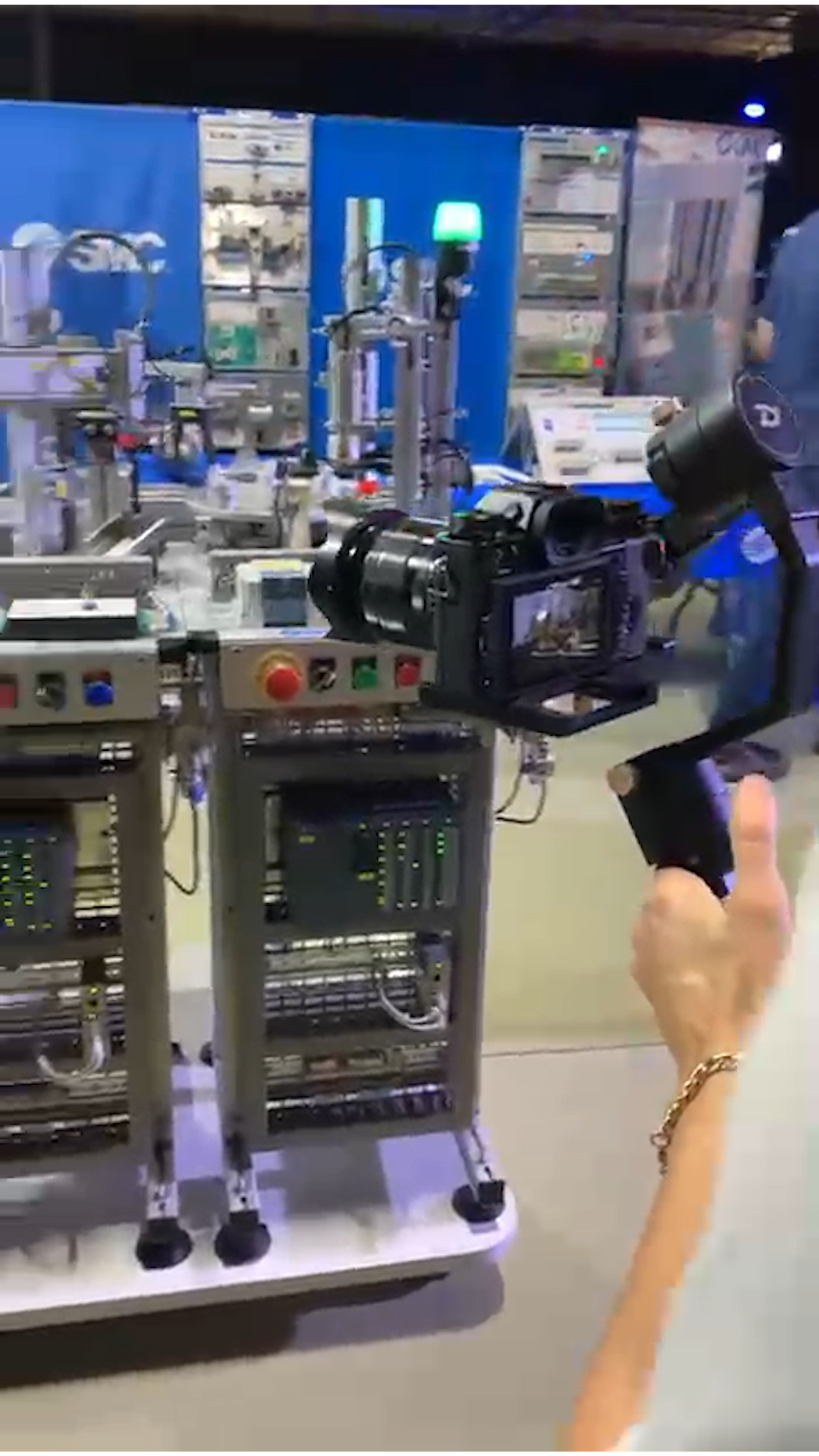 Behind the scenes at the expo, a gimbal-mounted camera filming an automation demonstration stand