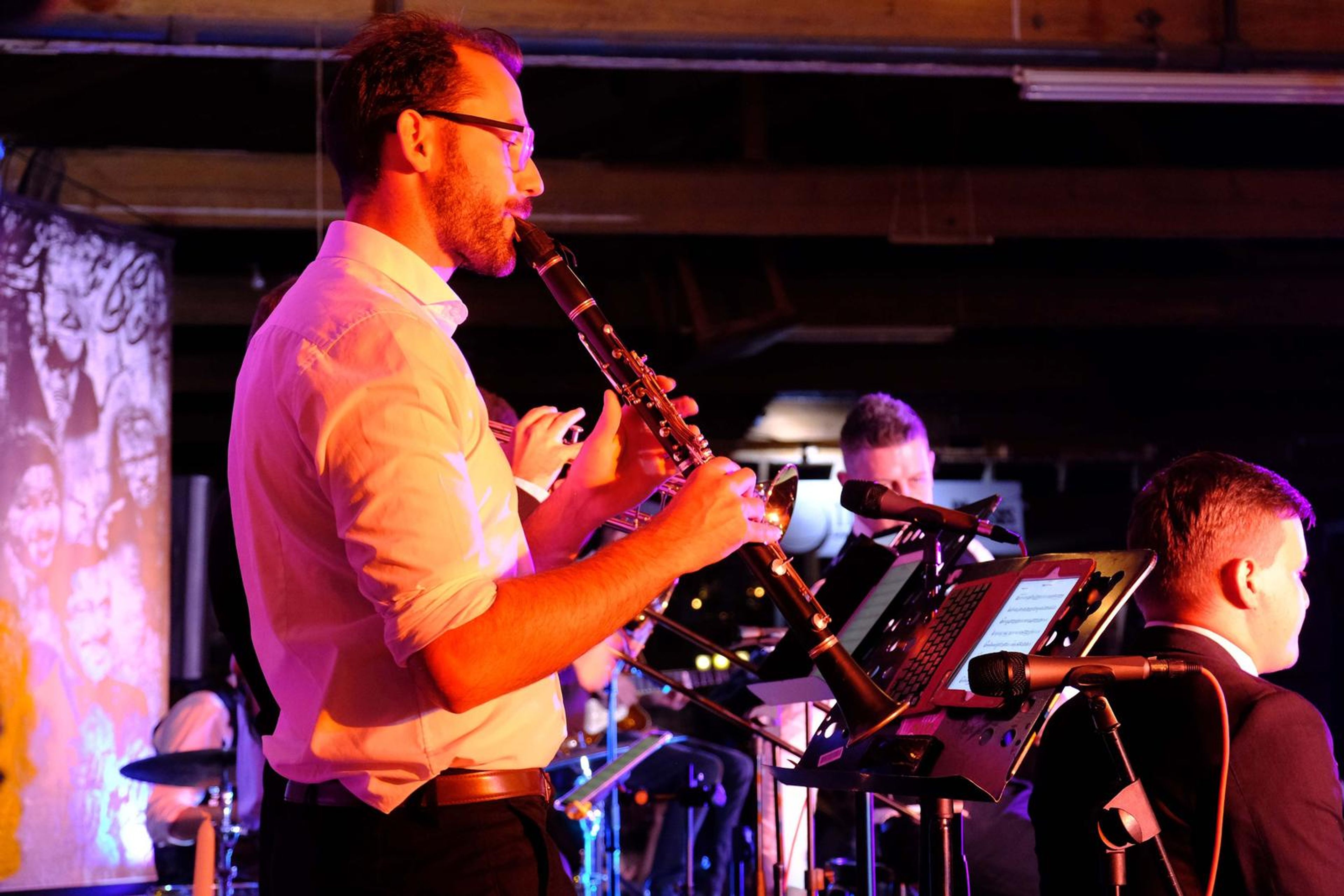 Clarinet player in a shirt playing under stage lights
