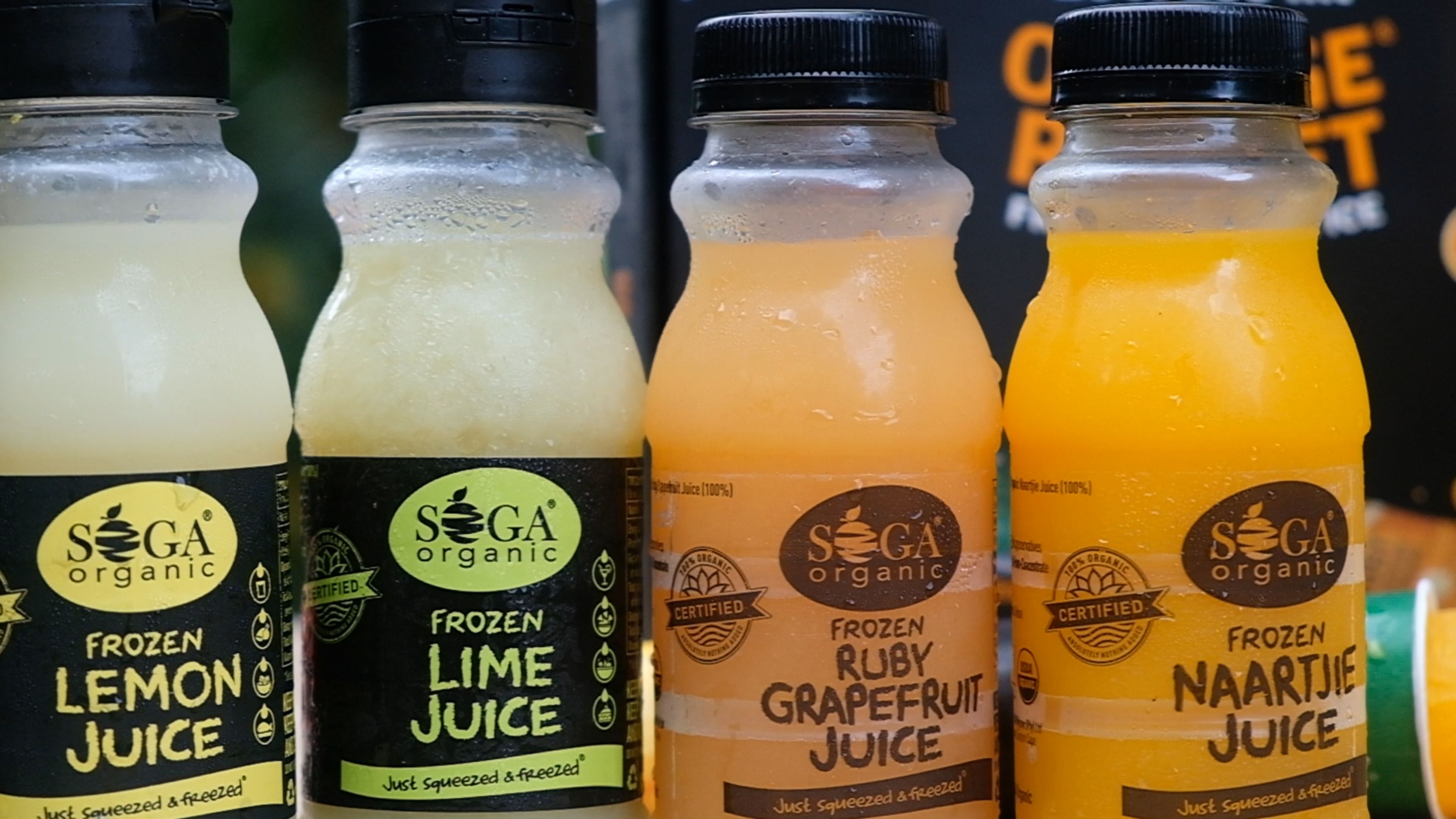 Row of SOGA frozen lemon, lime, ruby grapefruit and naartjie juice bottles