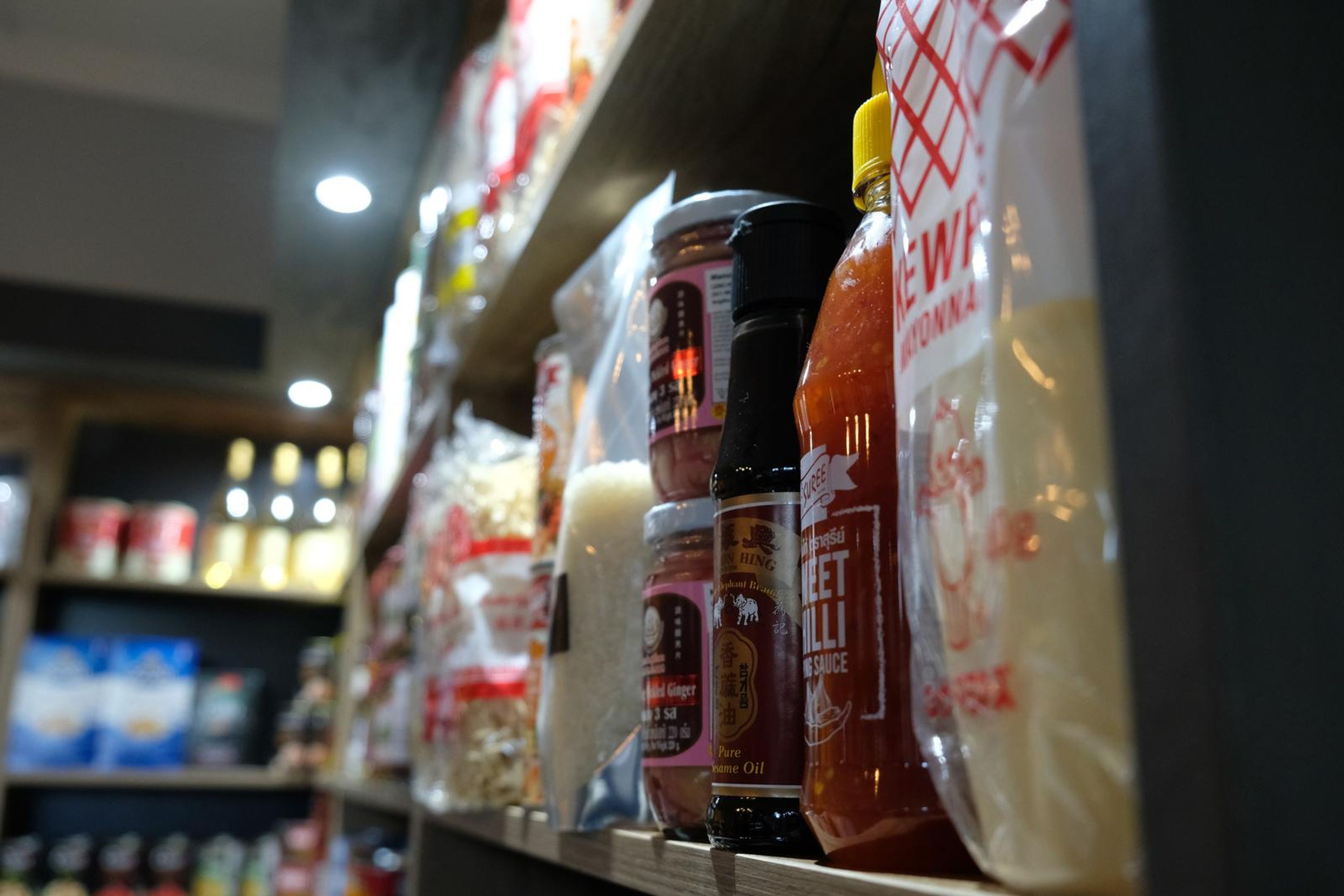 Shelf of Asian sauces and noodles in low light