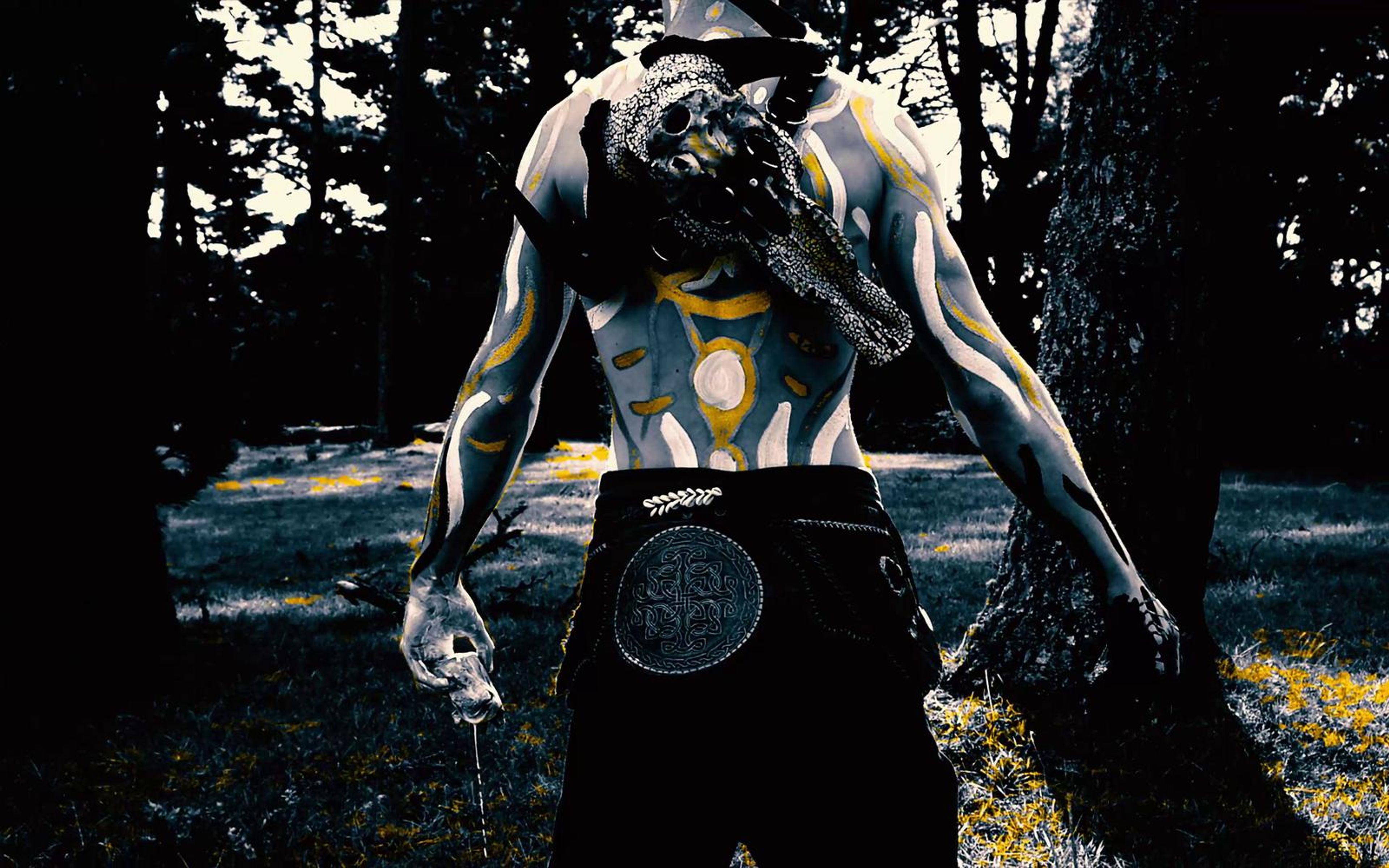 Performer from behind with arms hanging and a skull on his back on a forest road