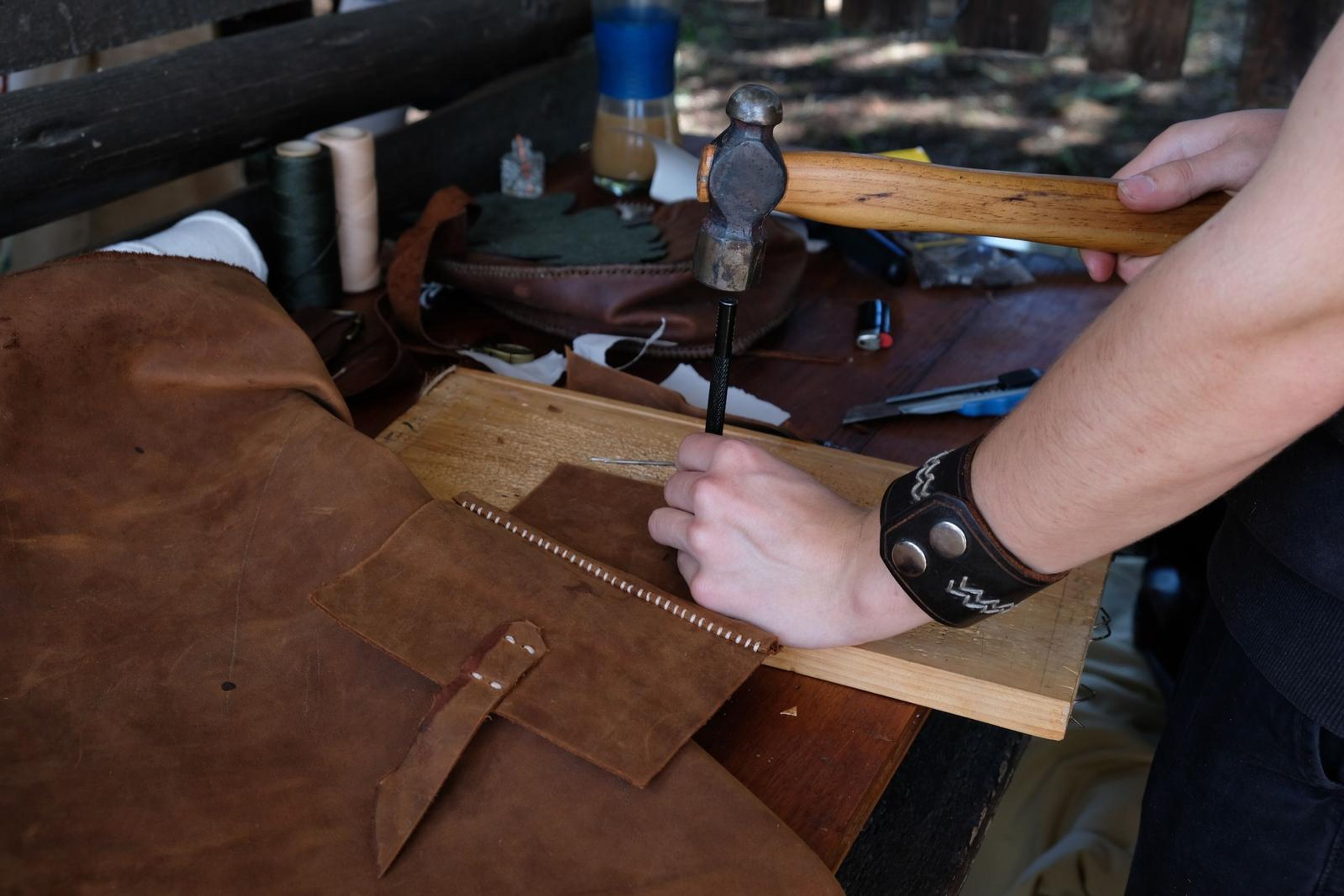 Hand punching stitch holes along the edge of a tan leather piece