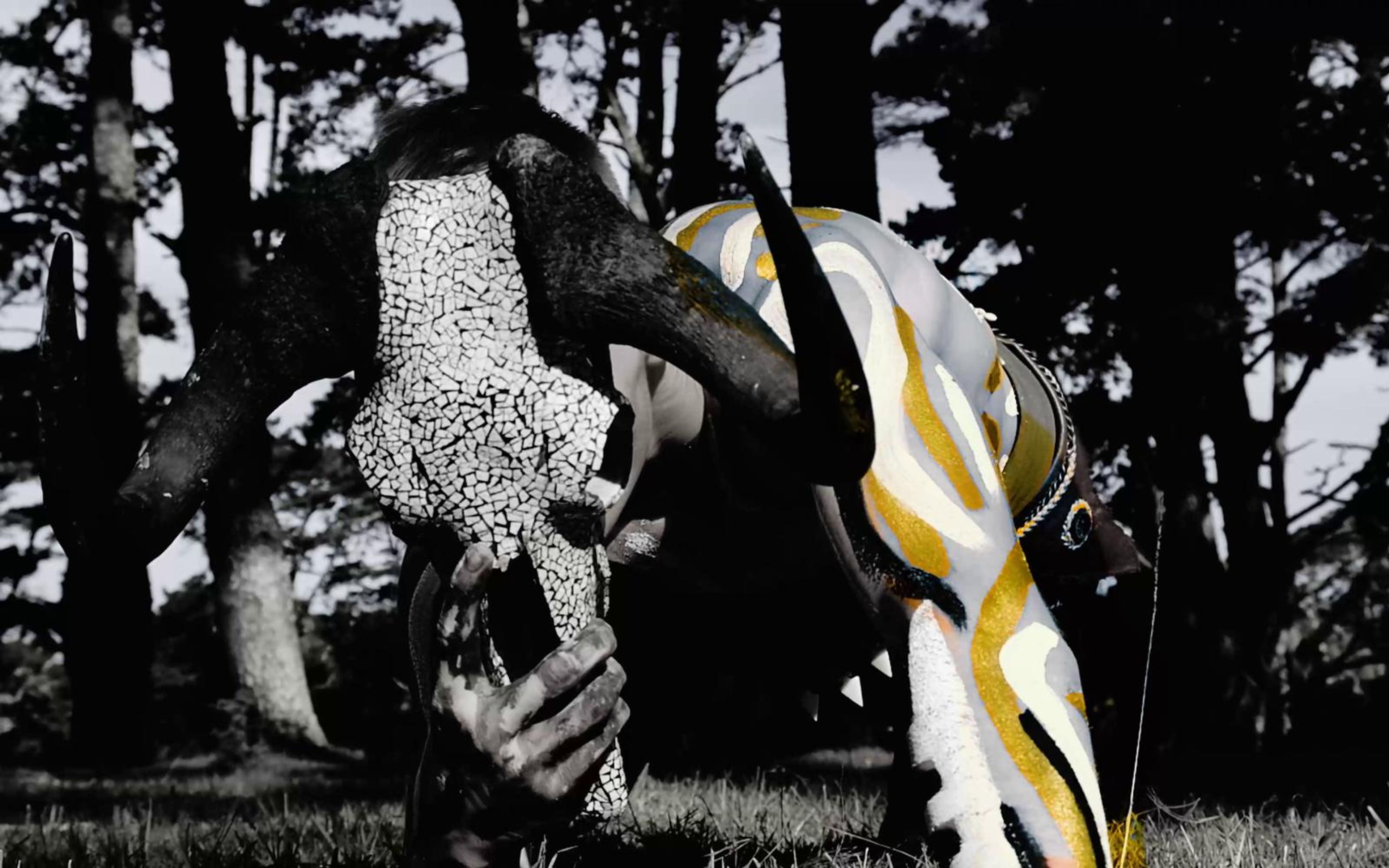 Skull with white dotted markings held beside a leg painted in yellow and white stripes
