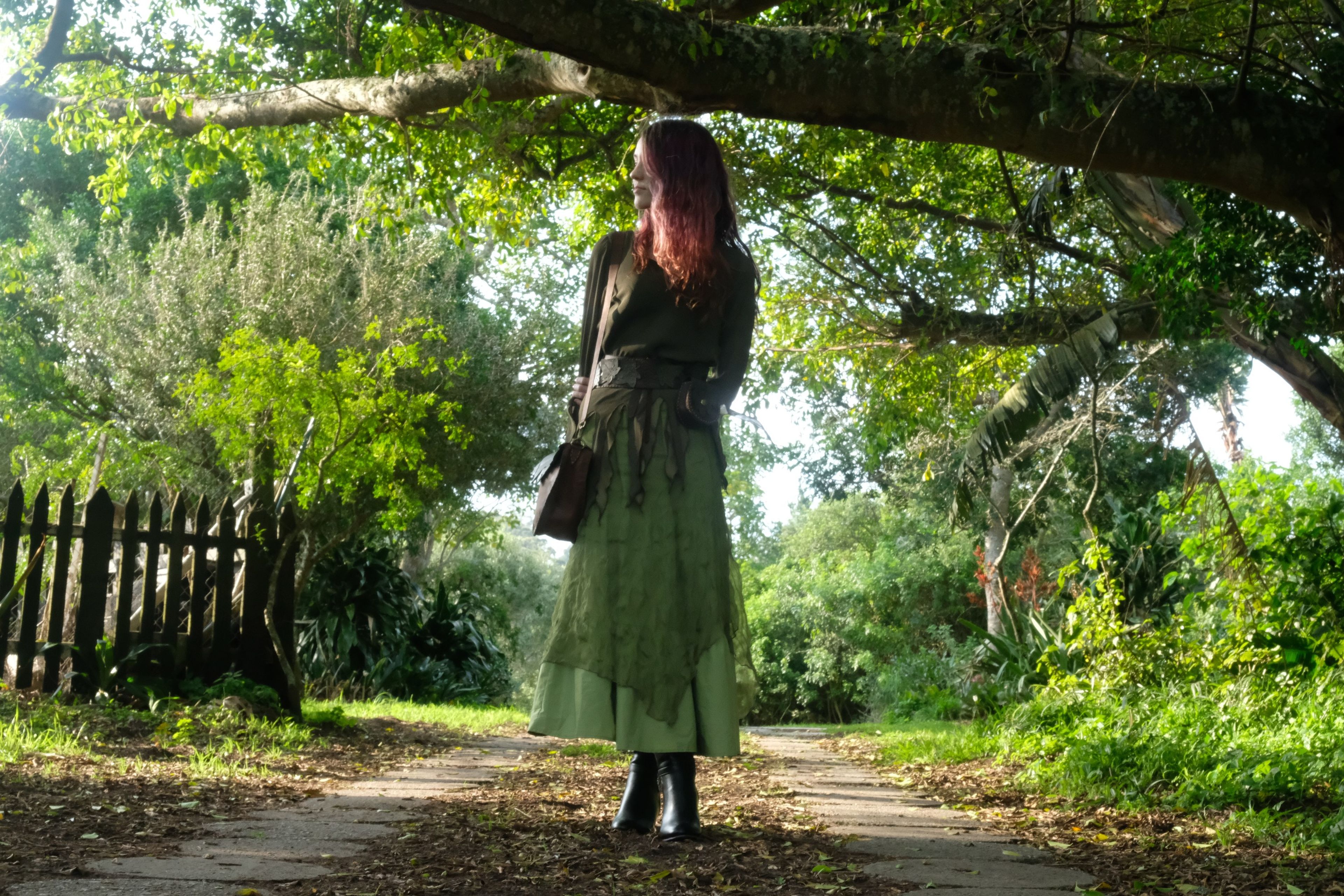 Woman in a long green skirt walking along a leafy path