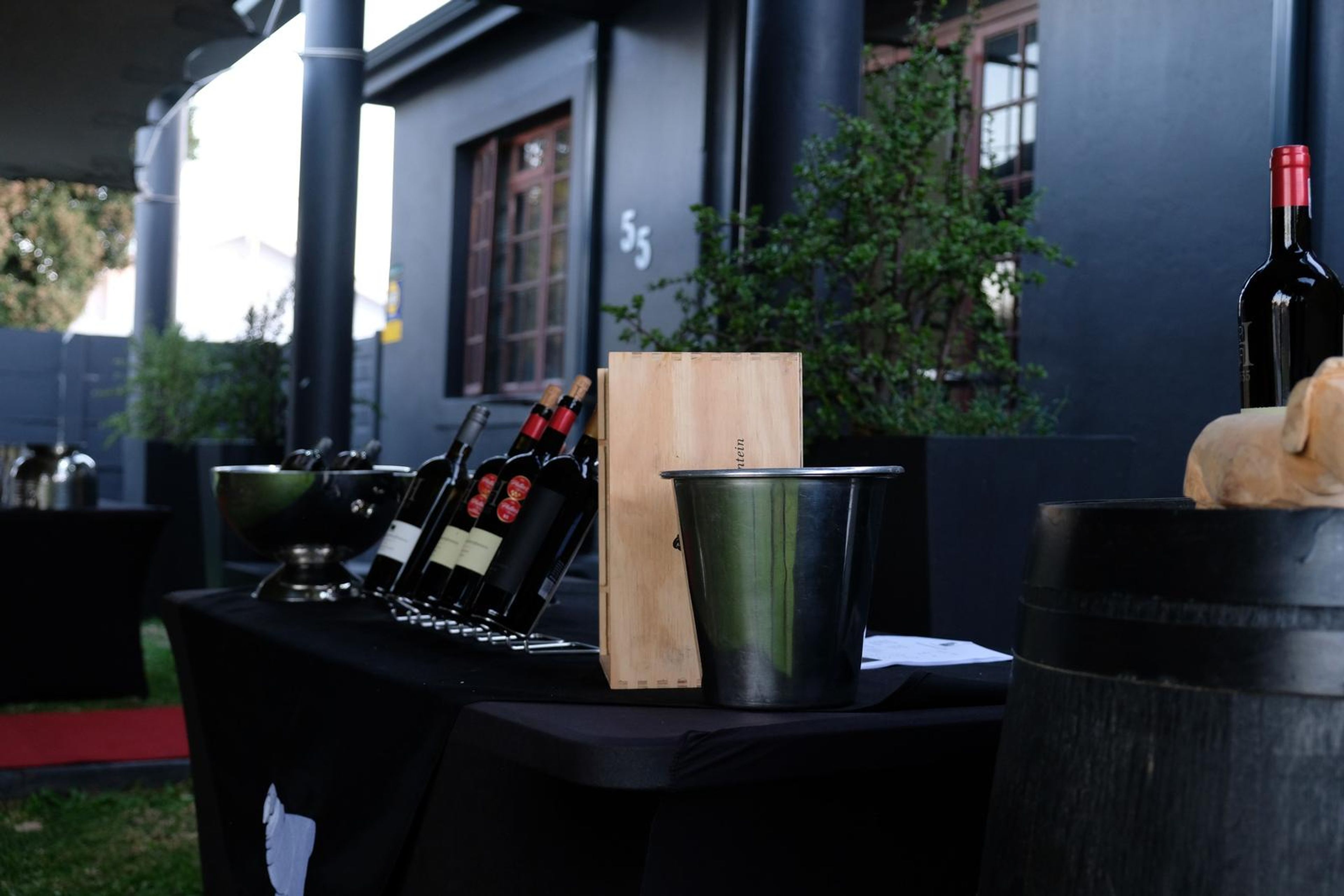 Wine tasting table on the lawn with bottles, barrel and ice bucket