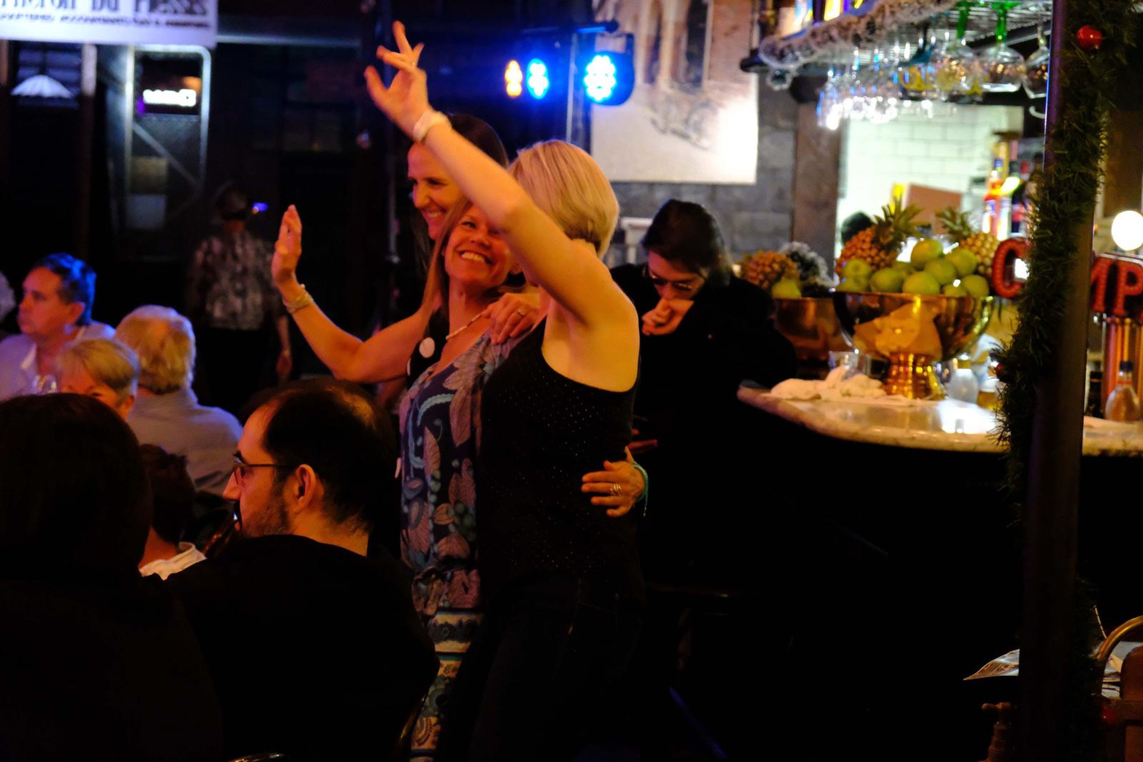 Guests dancing with their arms in the air by the bar