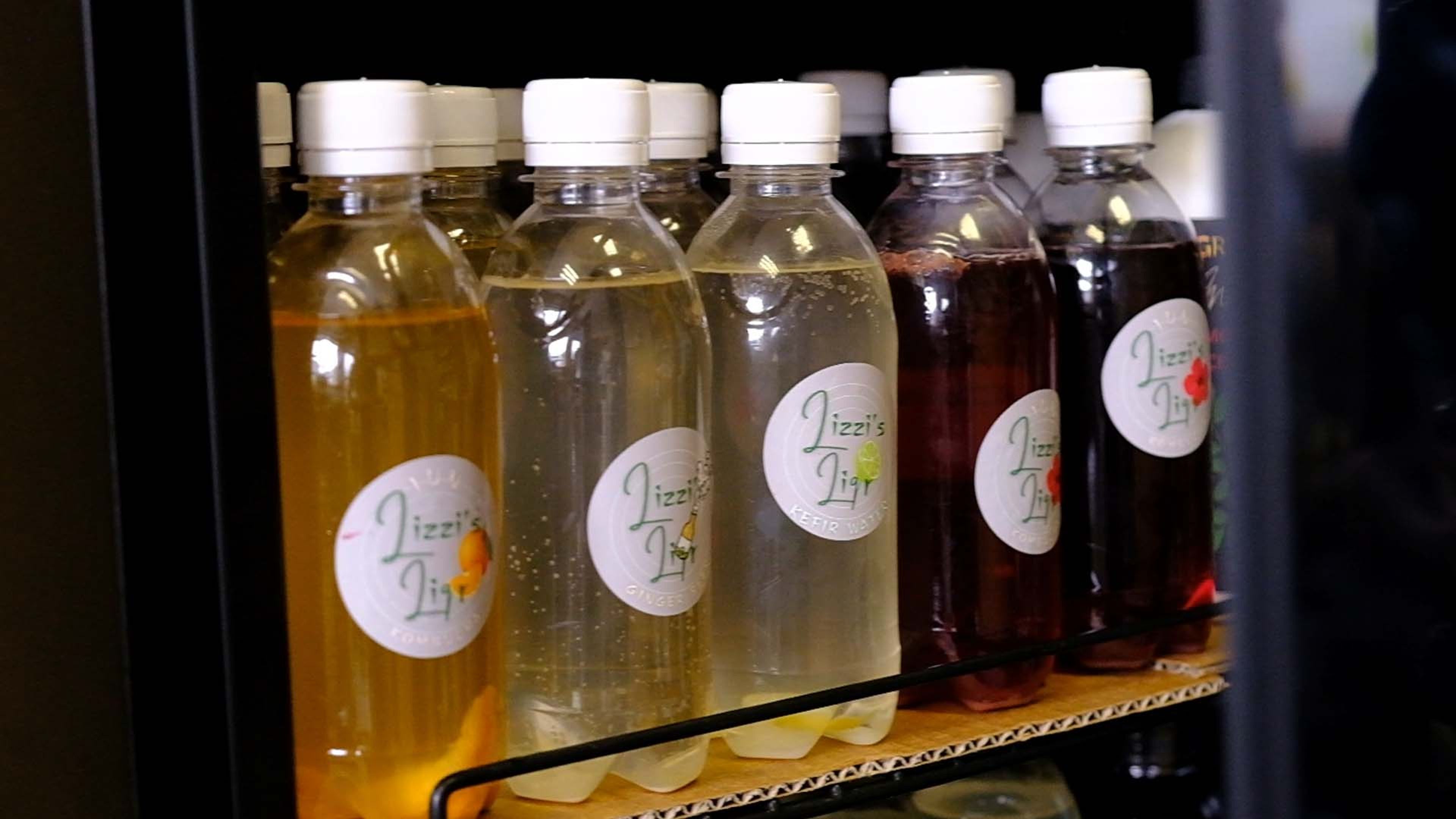 Bottles of homemade drinks with handwritten labels on a shelf