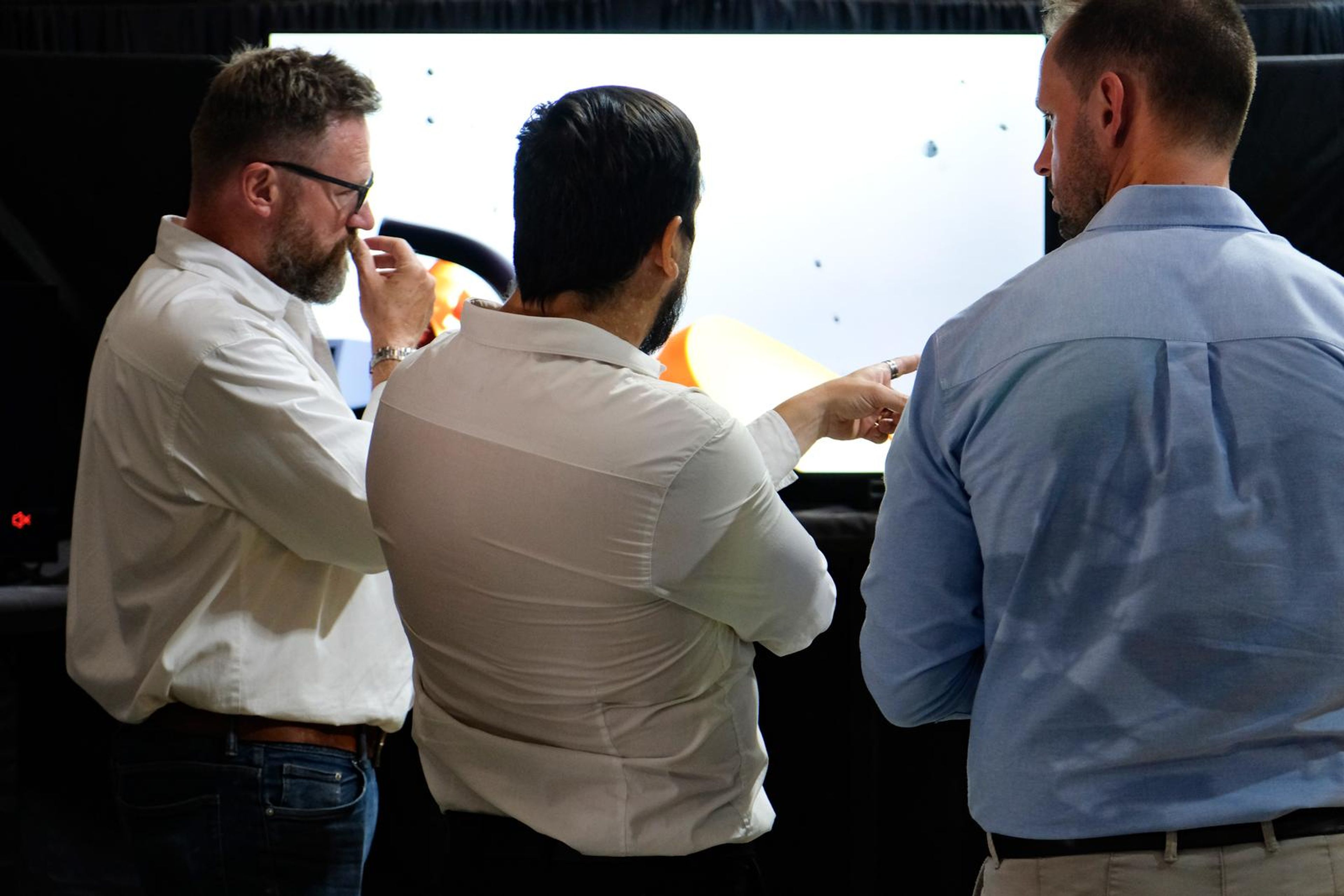 Team members discussing a simulation on a large display at the Symec stall