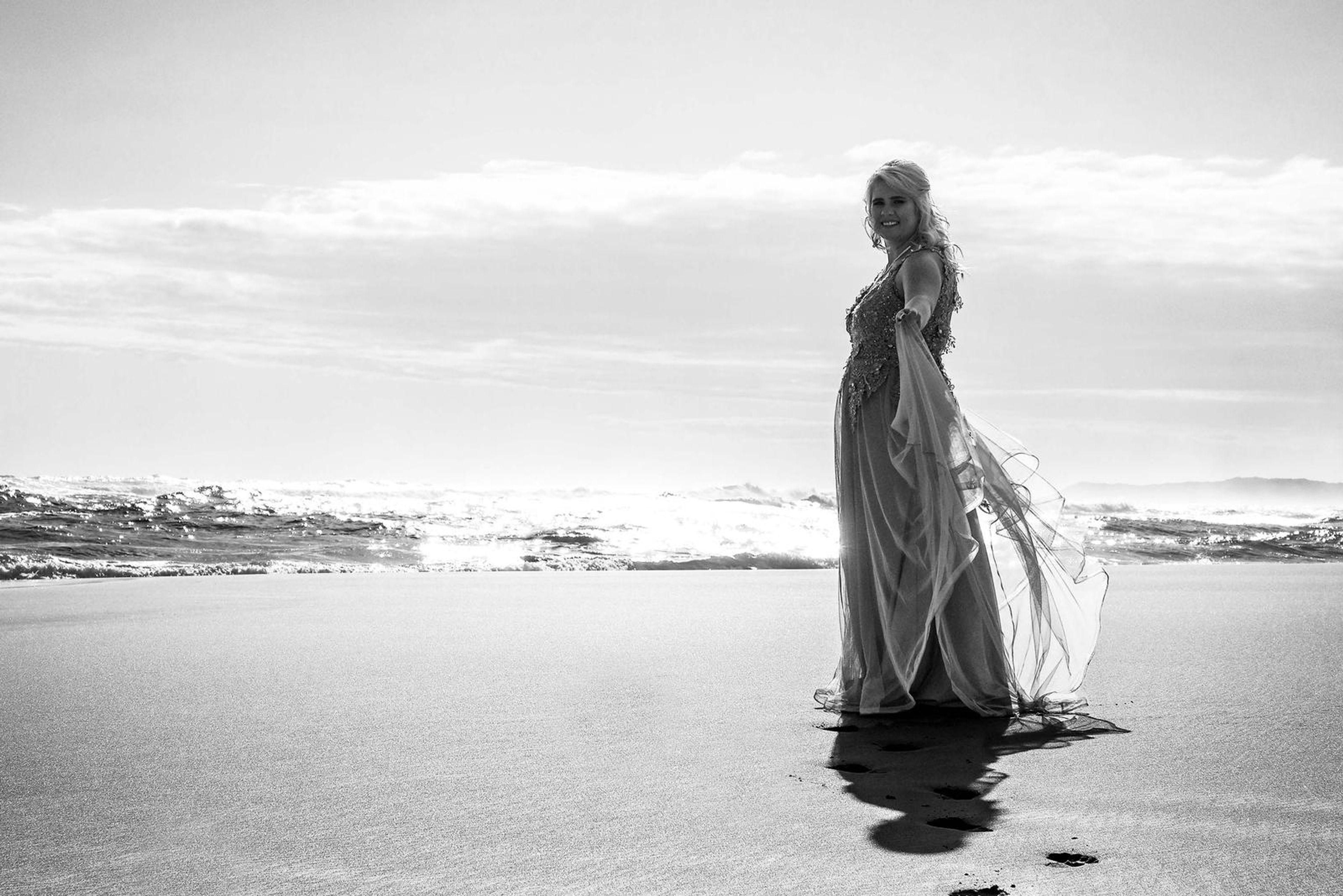 Black and white portrait standing on the shoreline in low sun