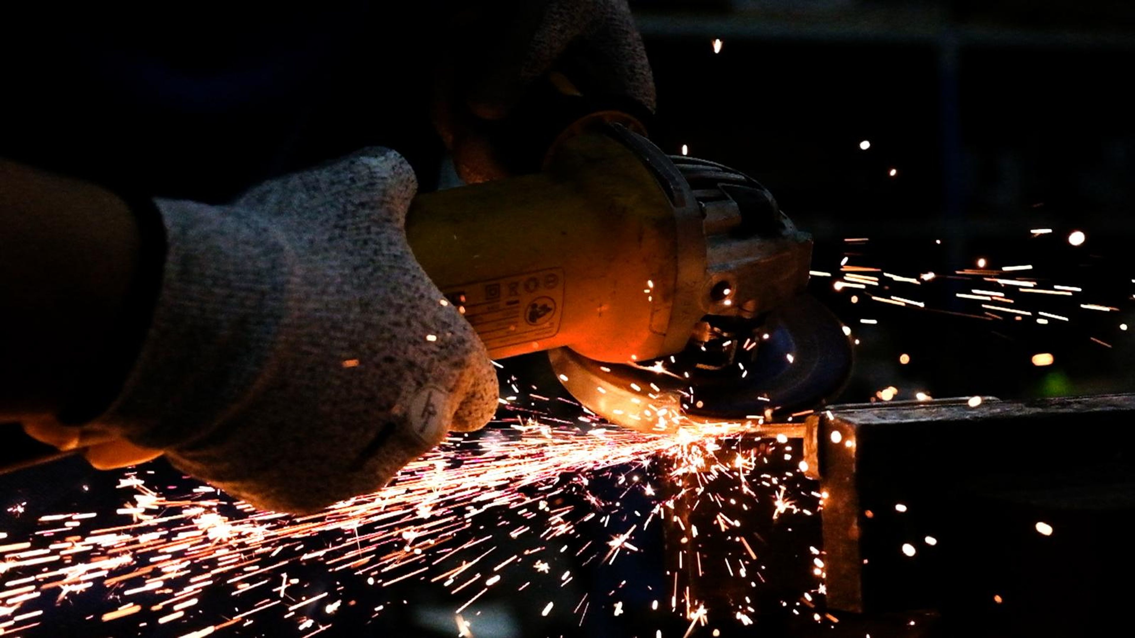 Burst of sparks from an angle grinder beside a gloved hand
