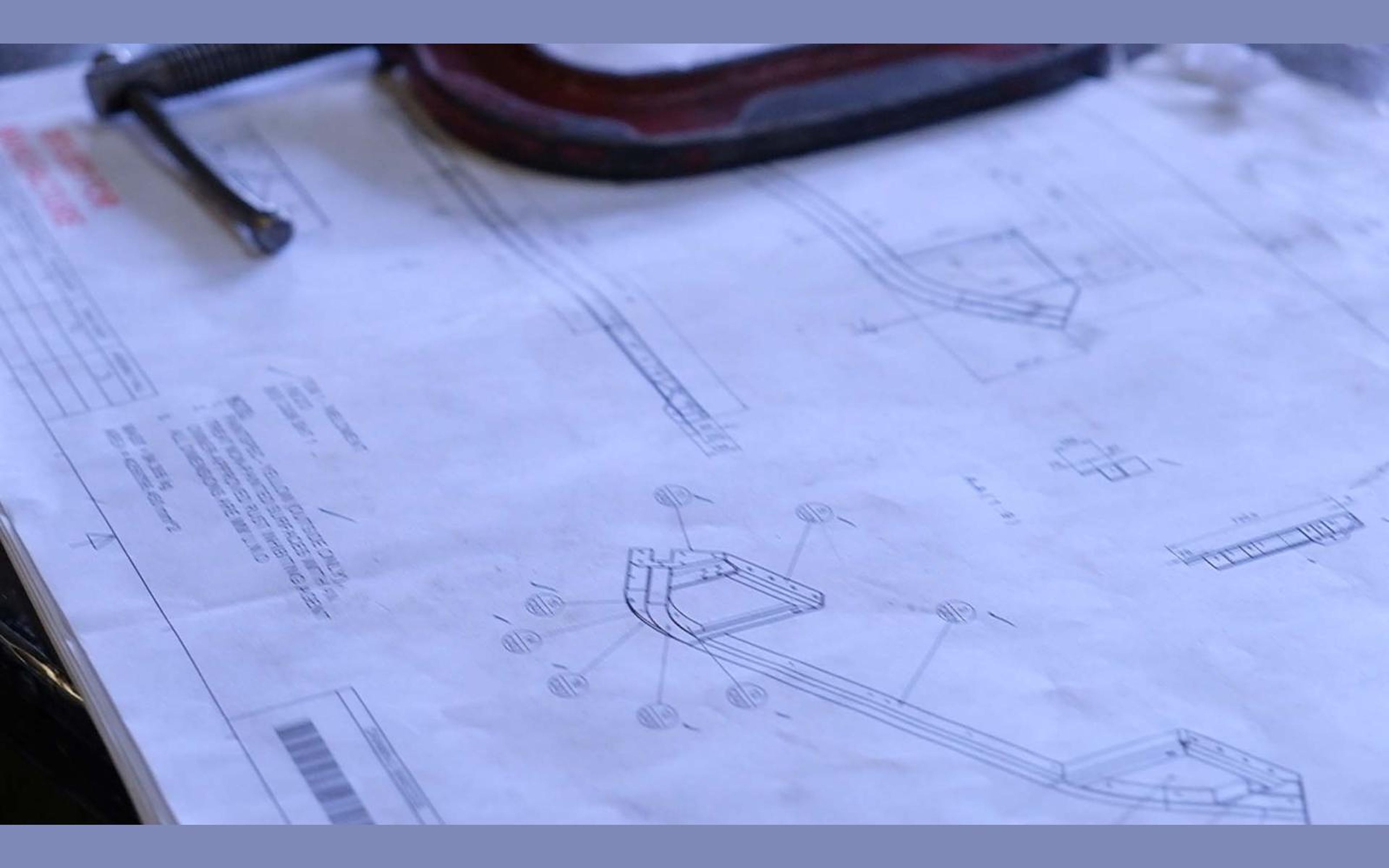 Technical drawing and steel clamp on a workbench