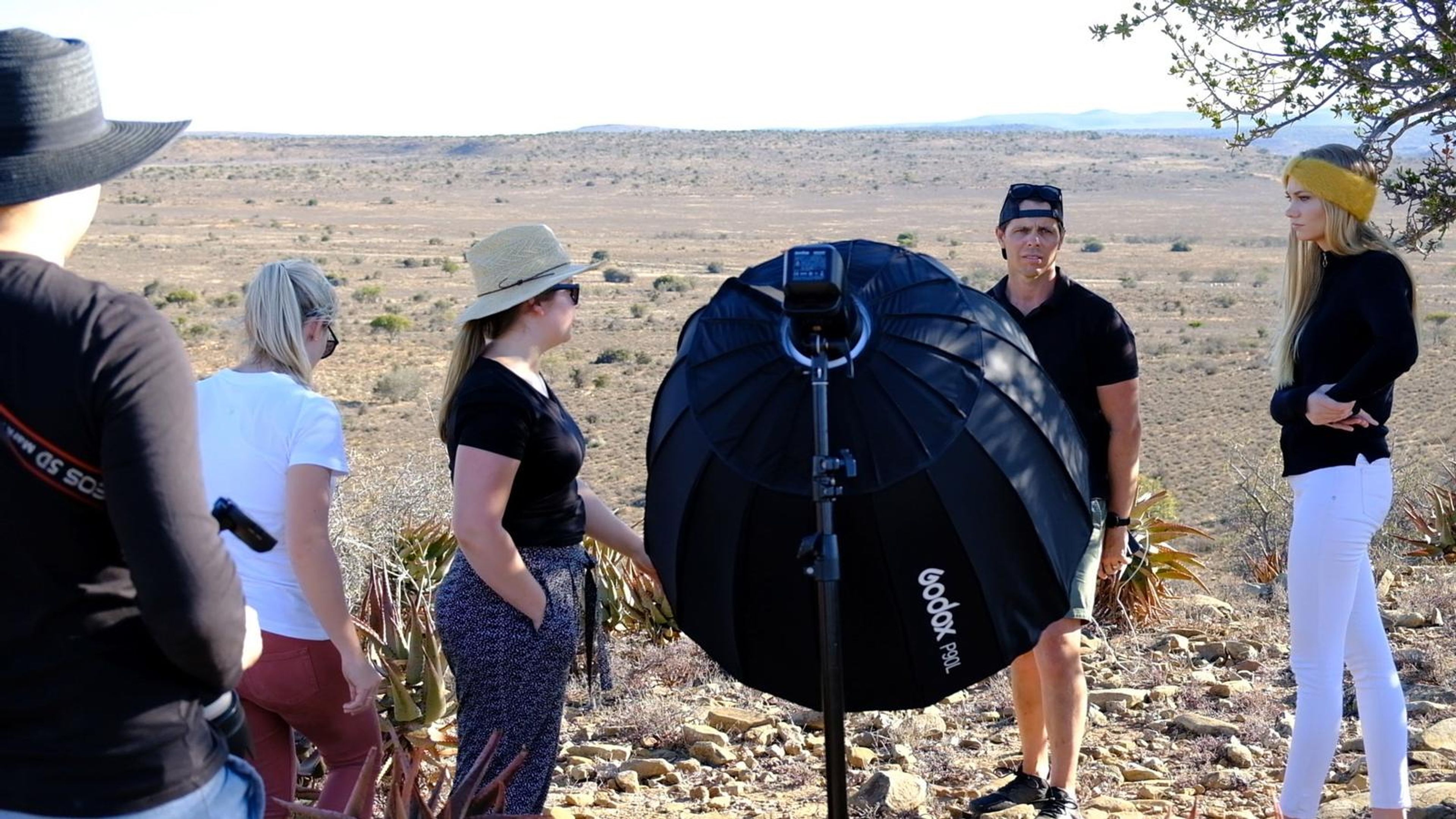 Crew and model gathered around a softbox on the hilltop