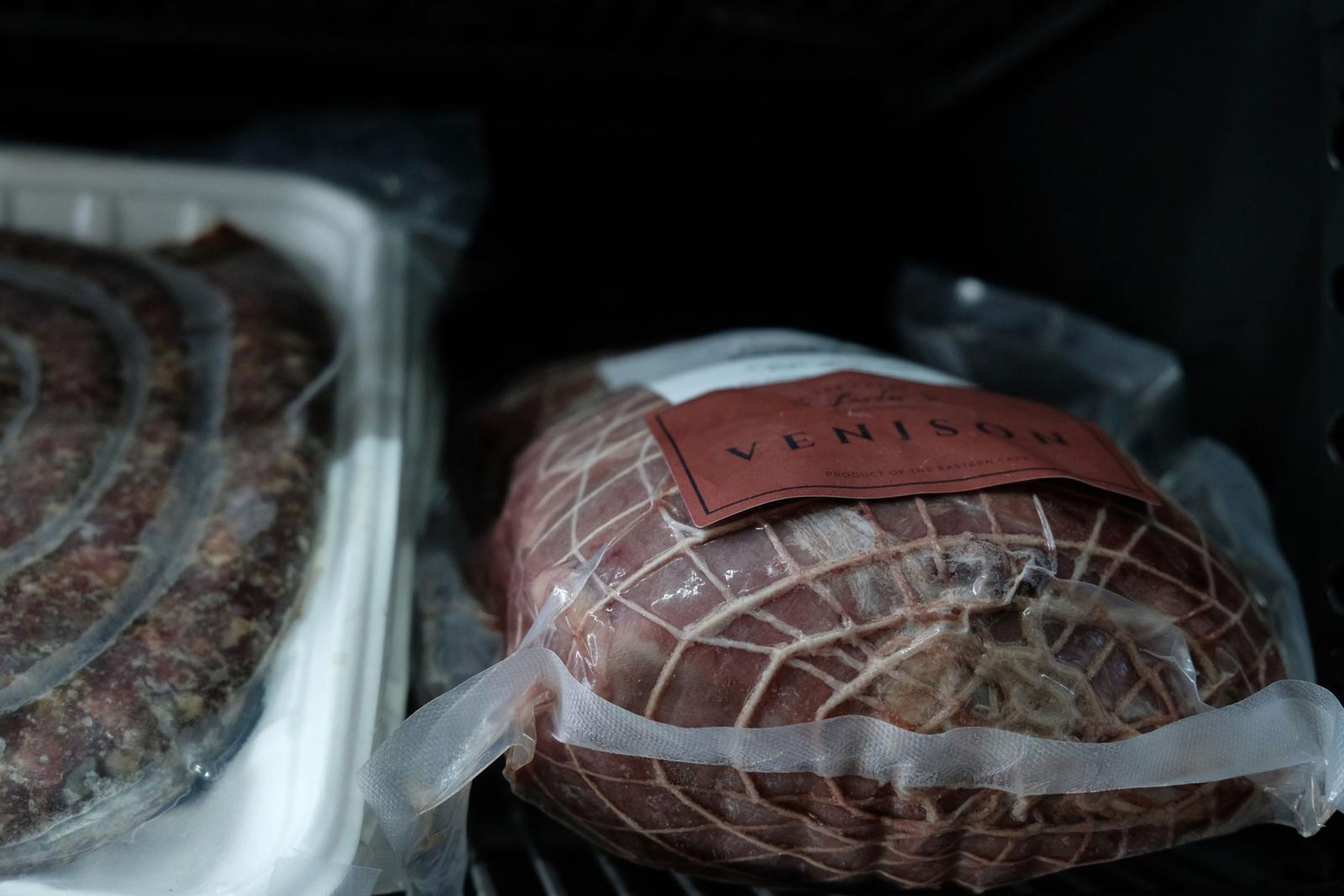 Netted venison roast beside a coil of sausage in the butchery fridge