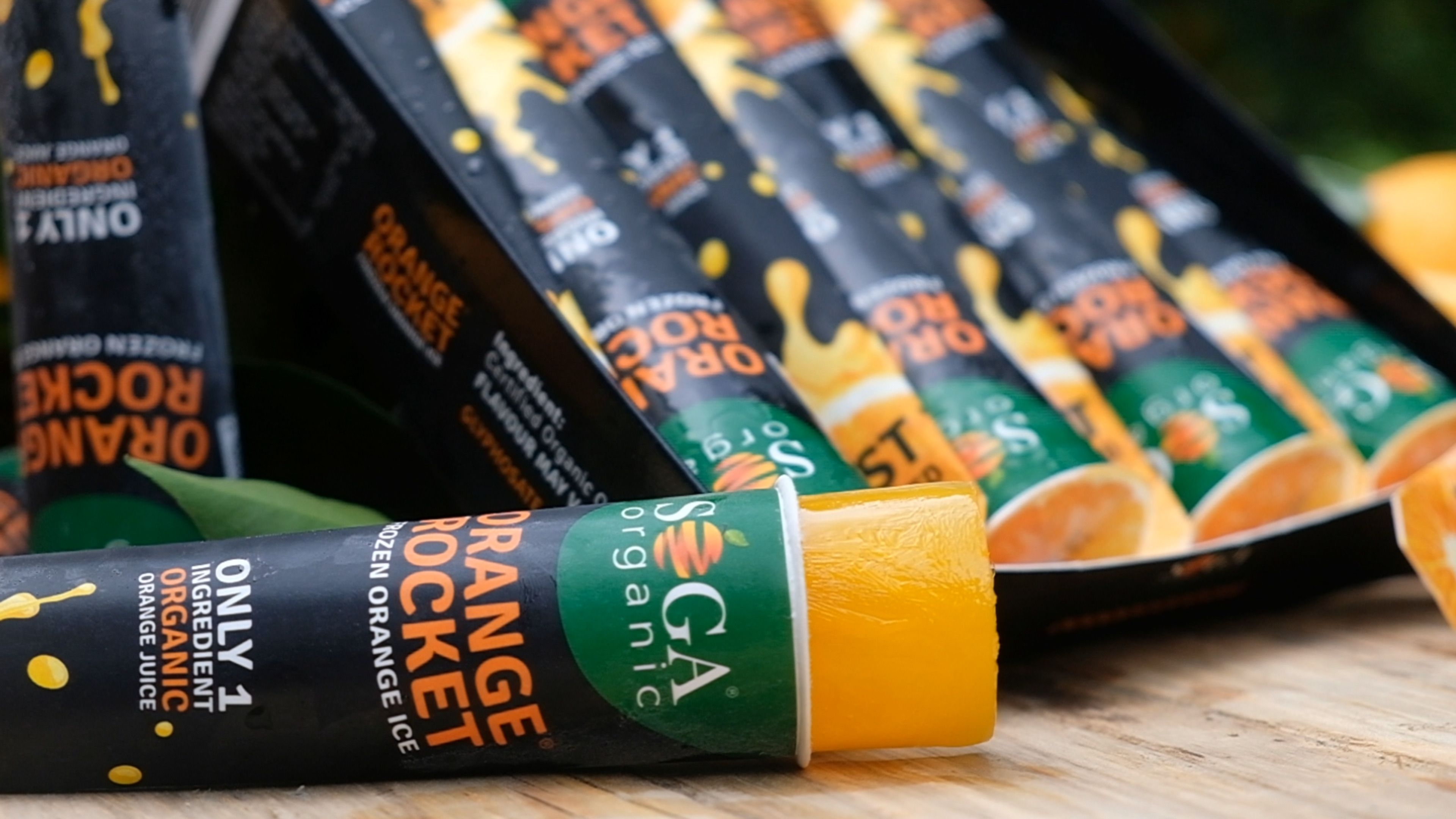 Orange Rocket tubes laid out on a wooden table with orange halves