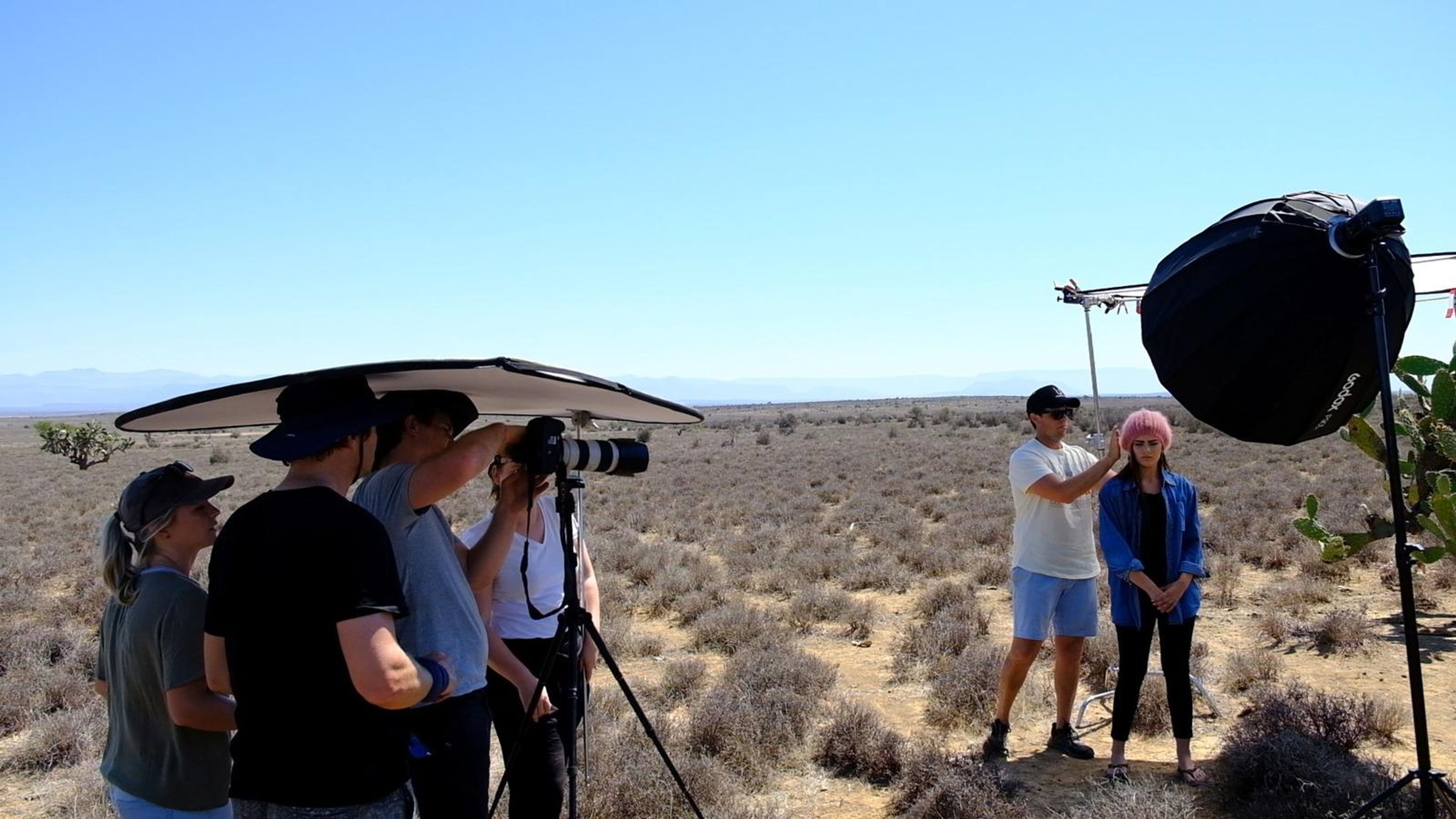 Crew gathered around the tripod as the model is lit by a softbox