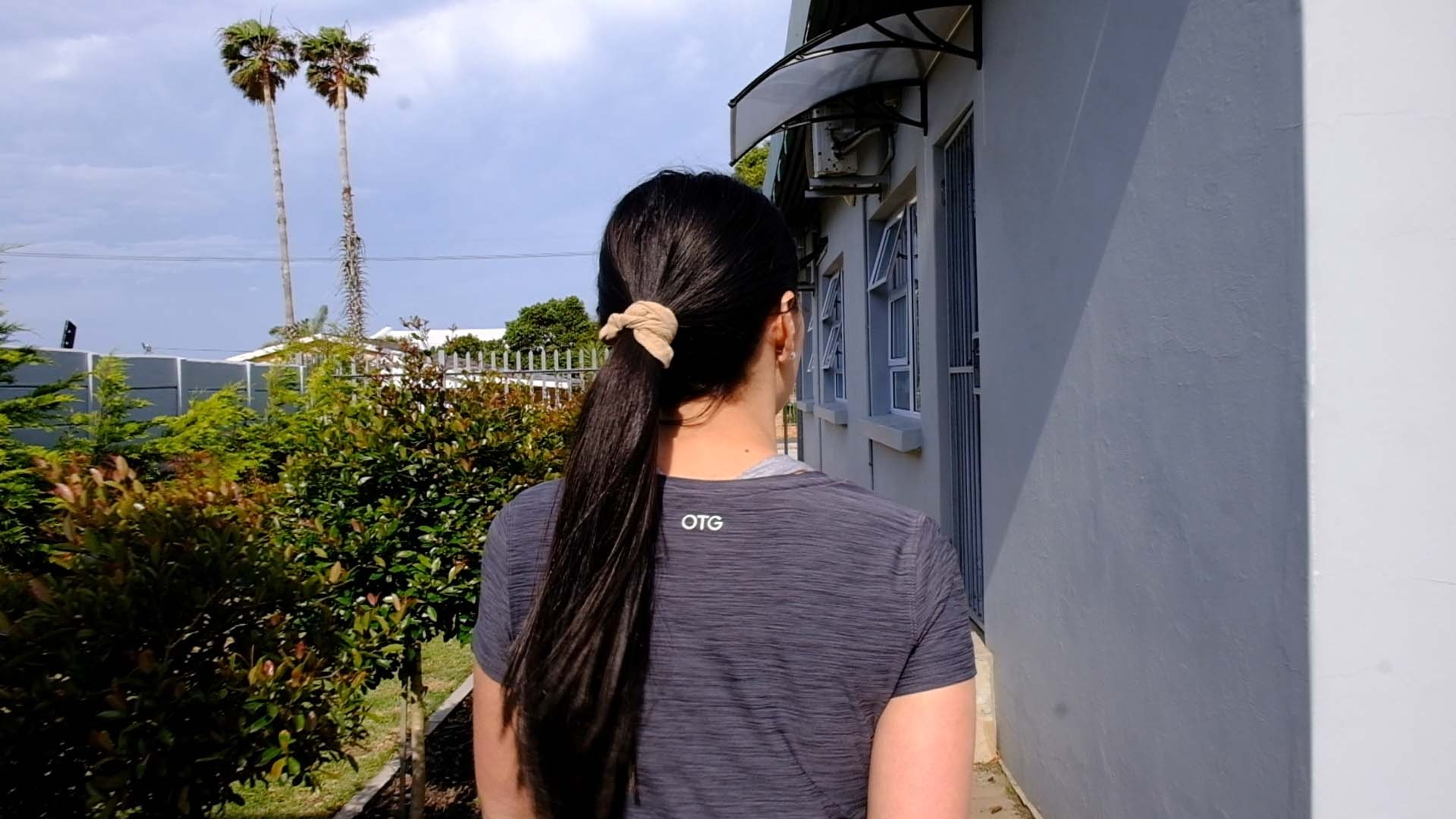 Staff member seen from behind outside the studio with palm trees in the background