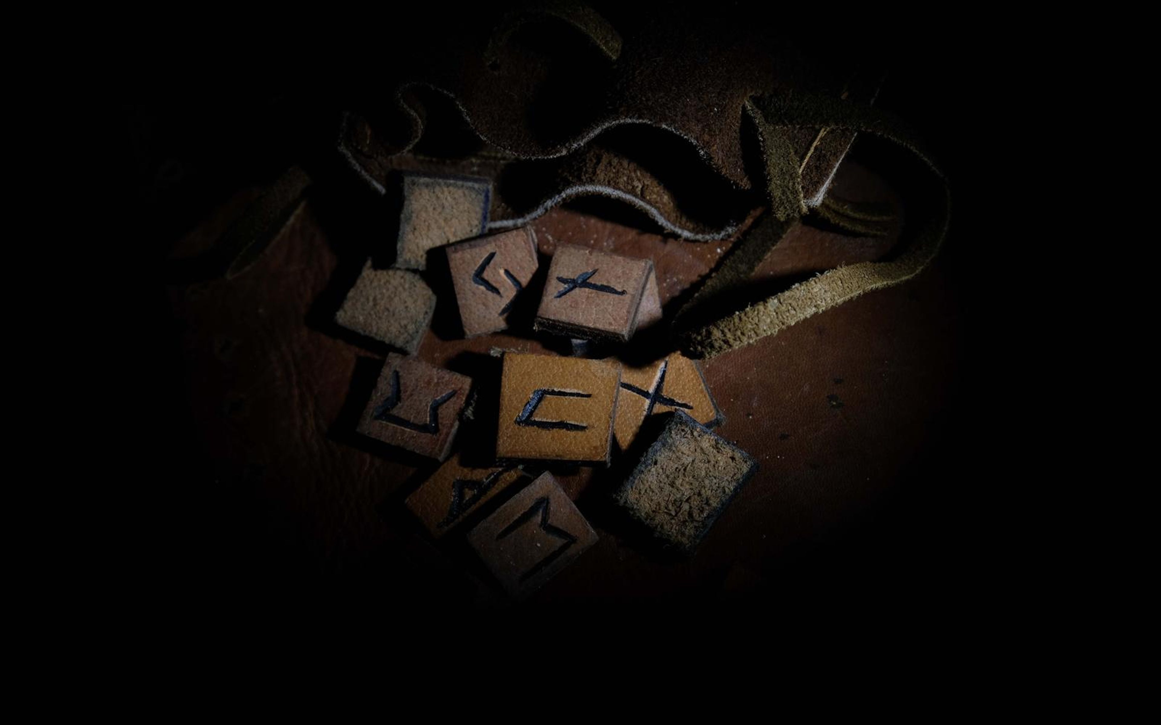 Leather rune tiles scattered over a brown hide in a warm pool of light fading to black