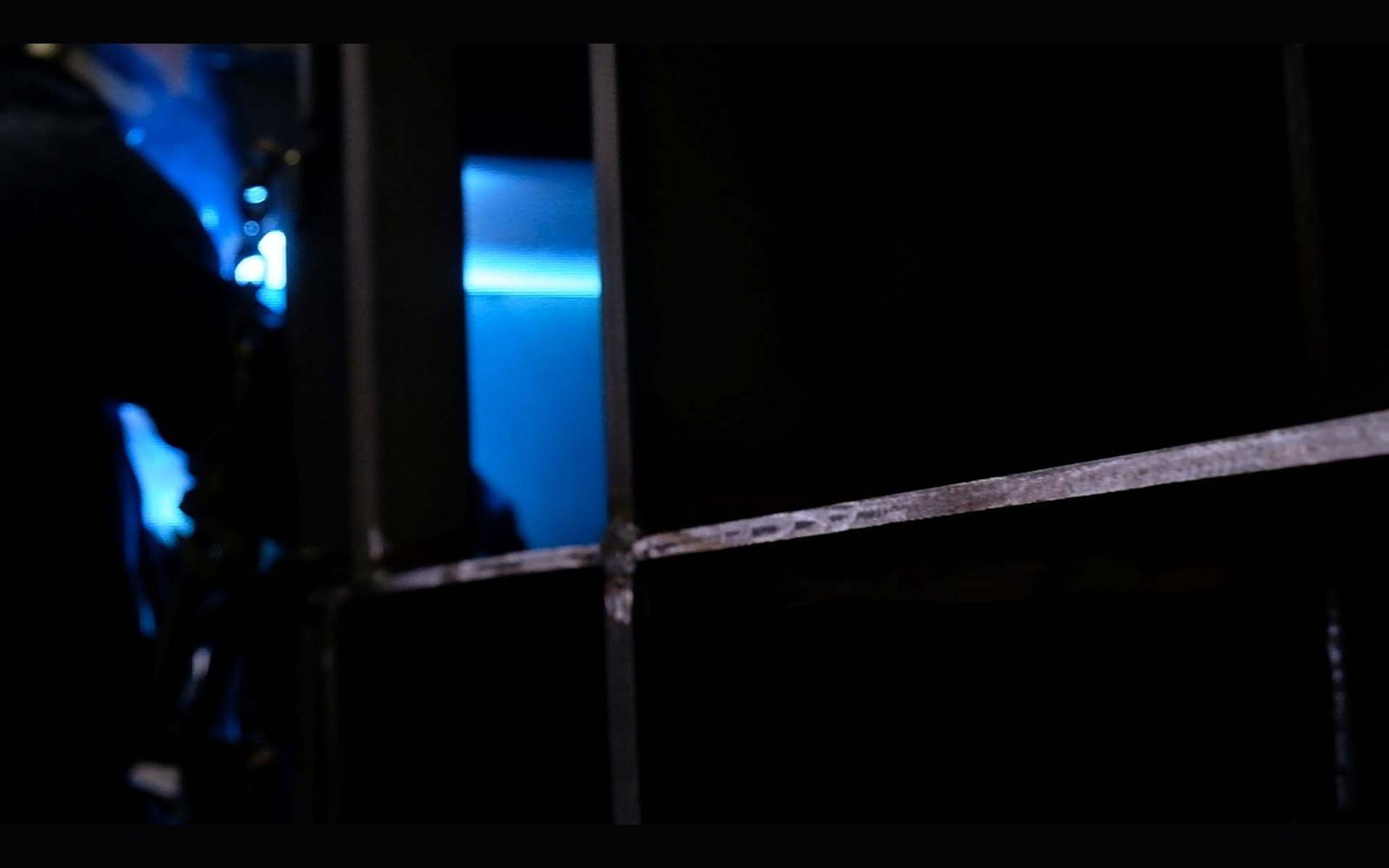Welder leaning over steel with a blue arc and sparks